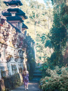 Girl in a purple kimono walking past an ancient an ancient temple on the Campuhan Ridge Walk in Ubud itinerary