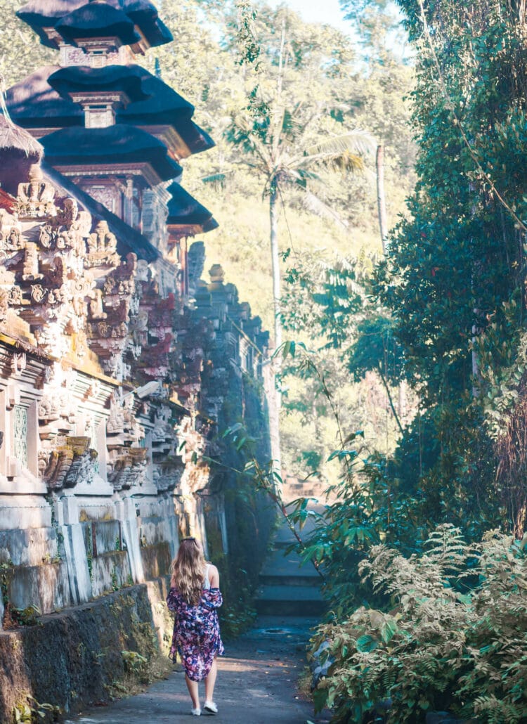Girl in a purple kimono walking past an ancient an ancient temple on the Campuhan Ridge Walk in Ubud itinerary