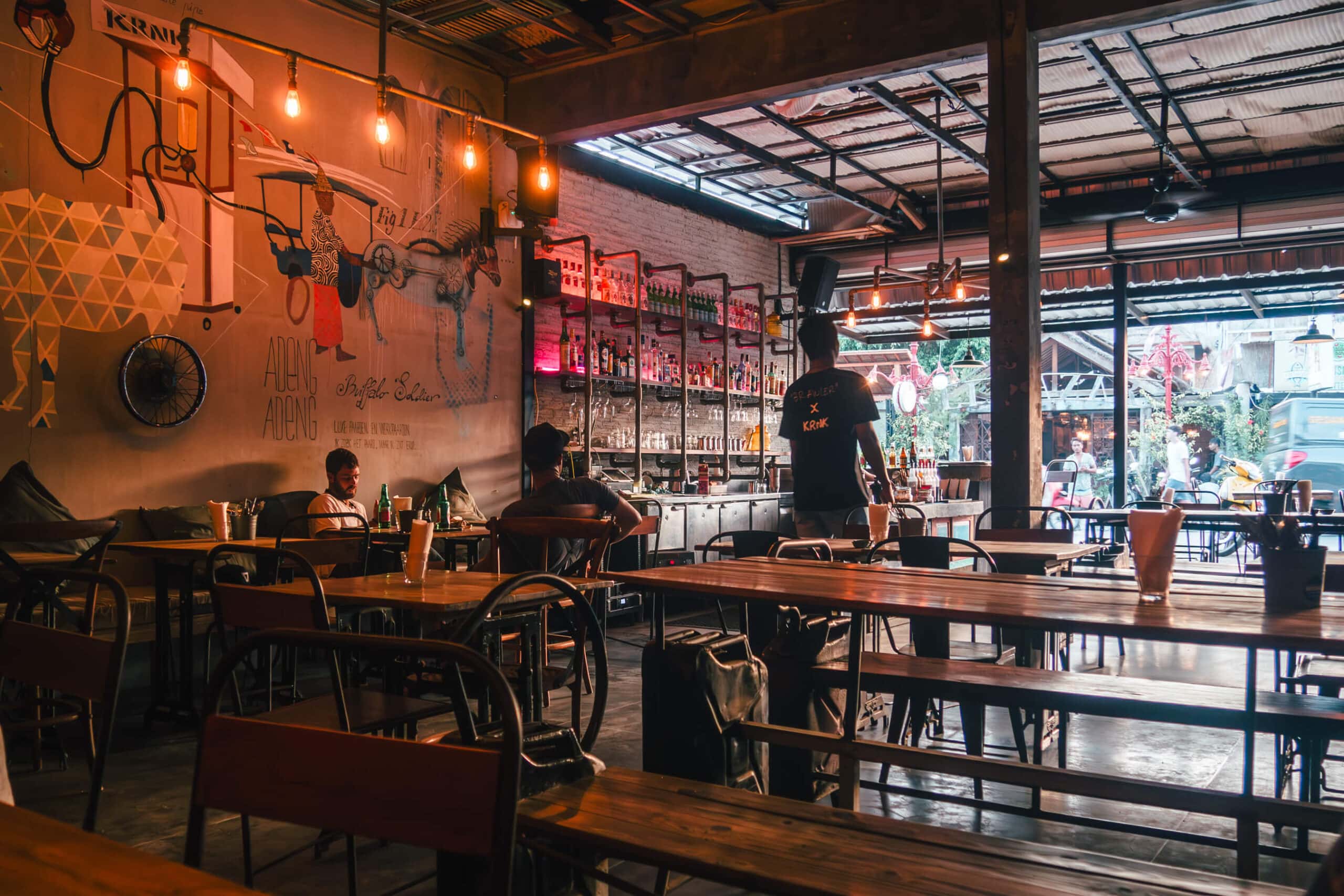 KRNK, a cool industrial restaurant with wooden tables and benches and dimmed lighting. One of the best restaurants Kuta Lombok.