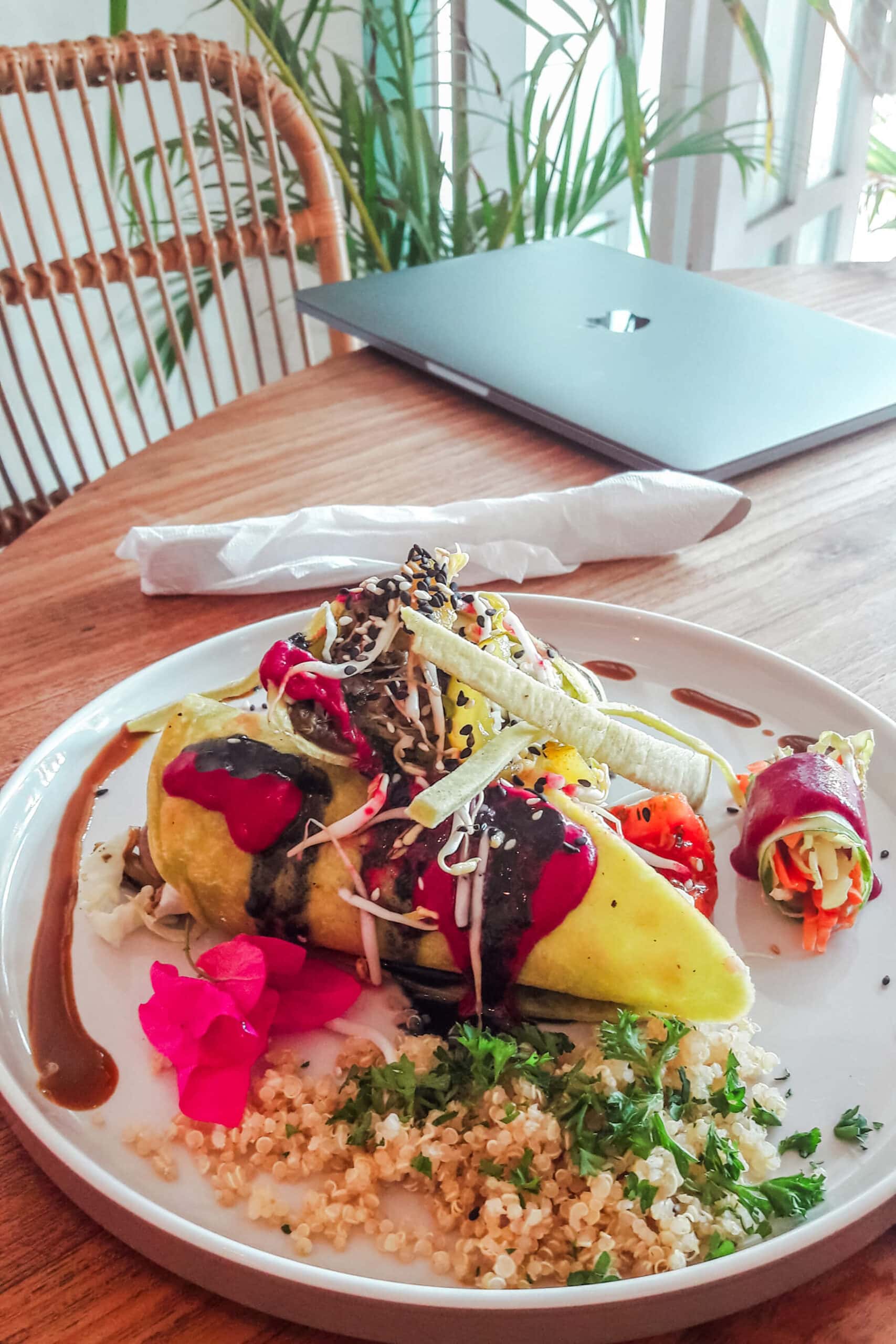 Vegetable wraps with purple sauce and flowers on a white plate in Kenza, one of the best restaurants in Kuta Lombok.