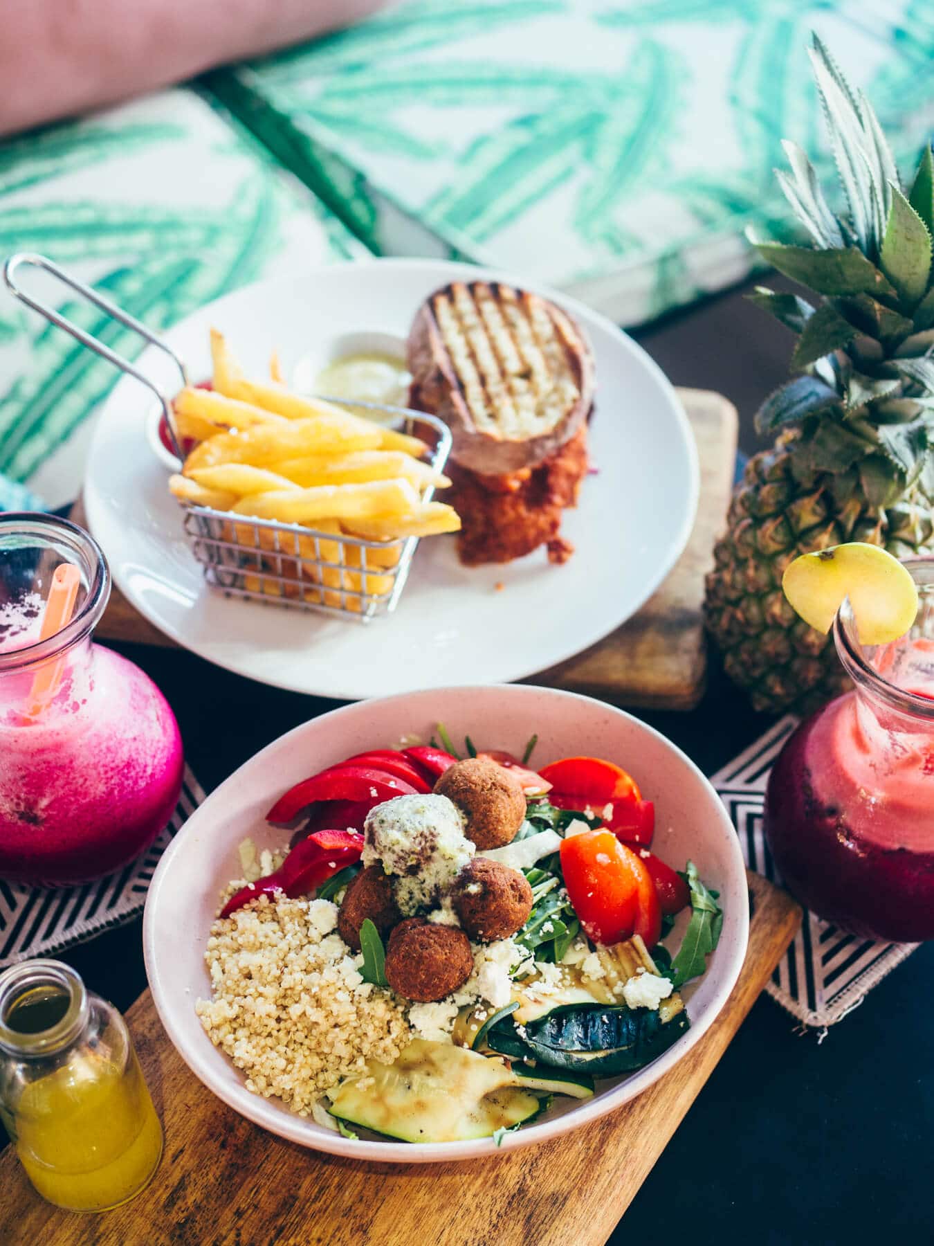 A falafel bowl and a fried chicken sandwich with fries and pink fruit juices at Milk Espresso, one of the best restaurants in Lombok.