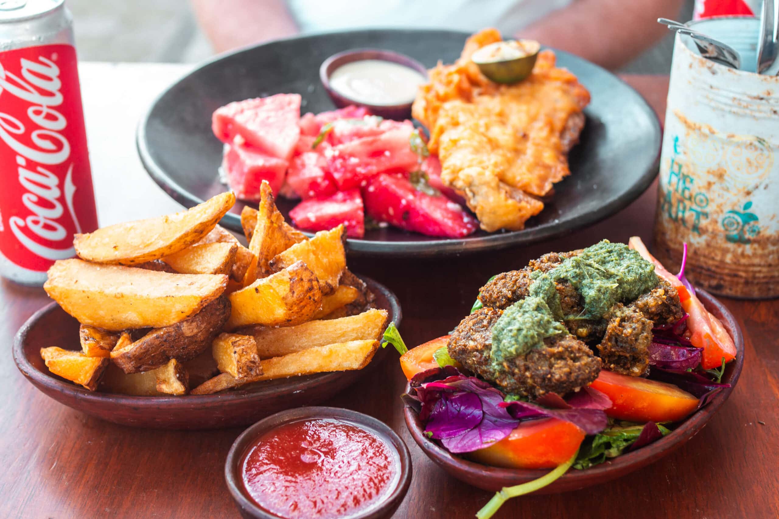 Handcut fries, ketchup, fried fish with watermelon and falafel on vegetable at SeaSalt, one of the best restaurants in Kuta Lombok.