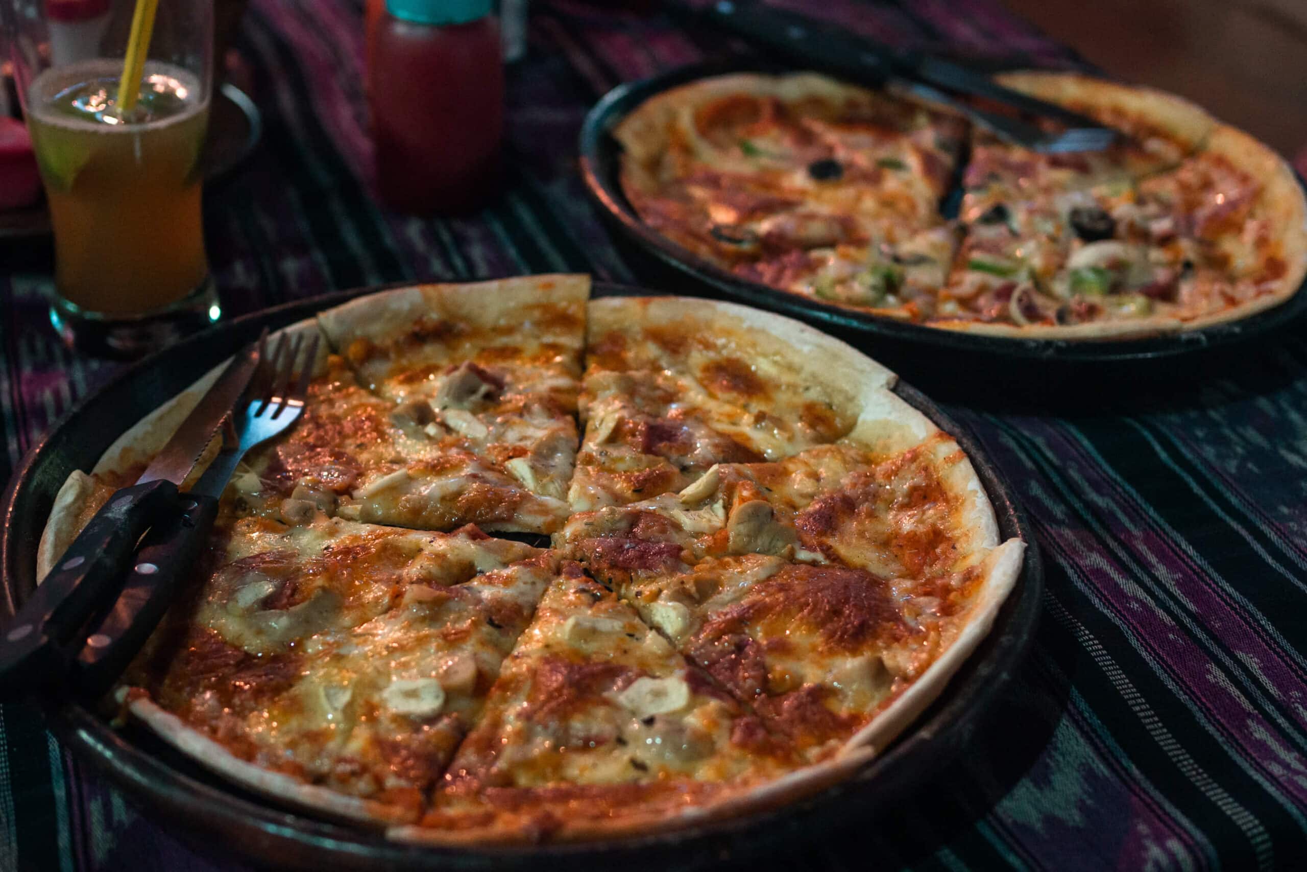 Two thin crust pizzas with an iced tea and coke in the background at Tomato Cafe, one of my favorite restaurants in Kuta Lombok.