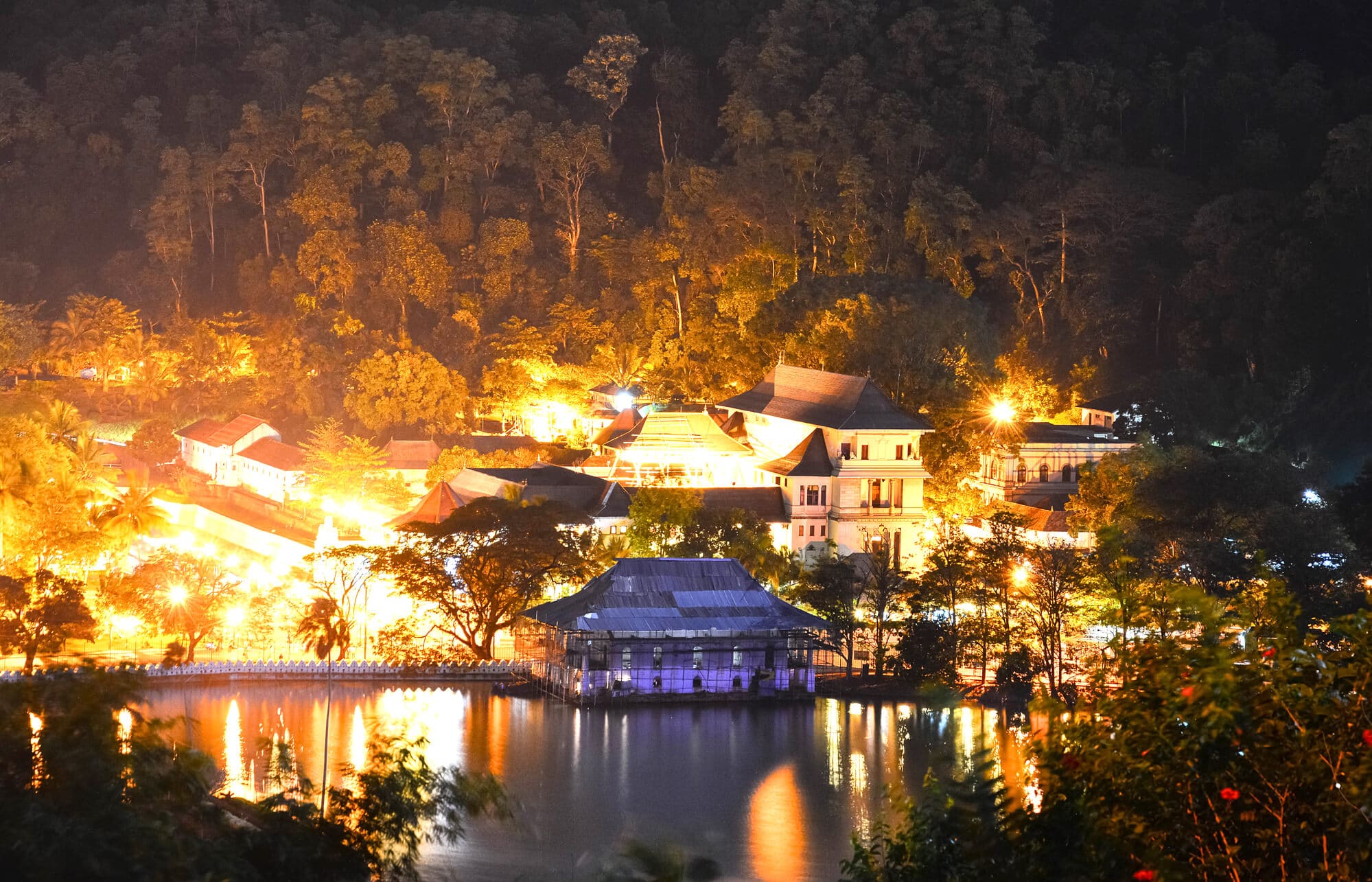 Nighttime view of Kandy Lake and the Royal Palace lit up by yellow lights, two of the best places to visit in Kandy.