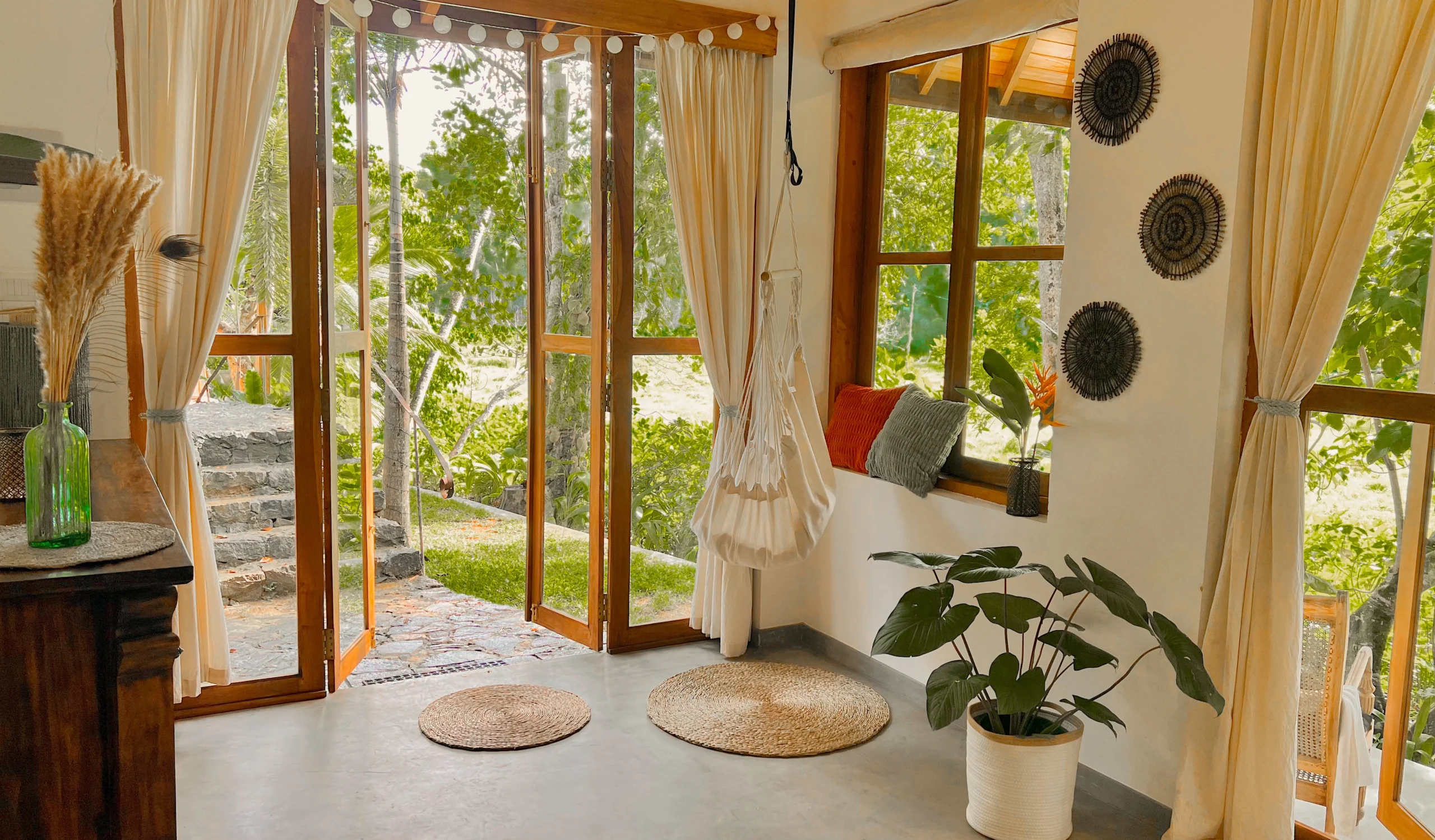 Light and bright living area with large wood frame door and windows looking out over the jungle at the Jungle Loft Galle, one of the best and most affordable Airbnbs Sri Lanka.