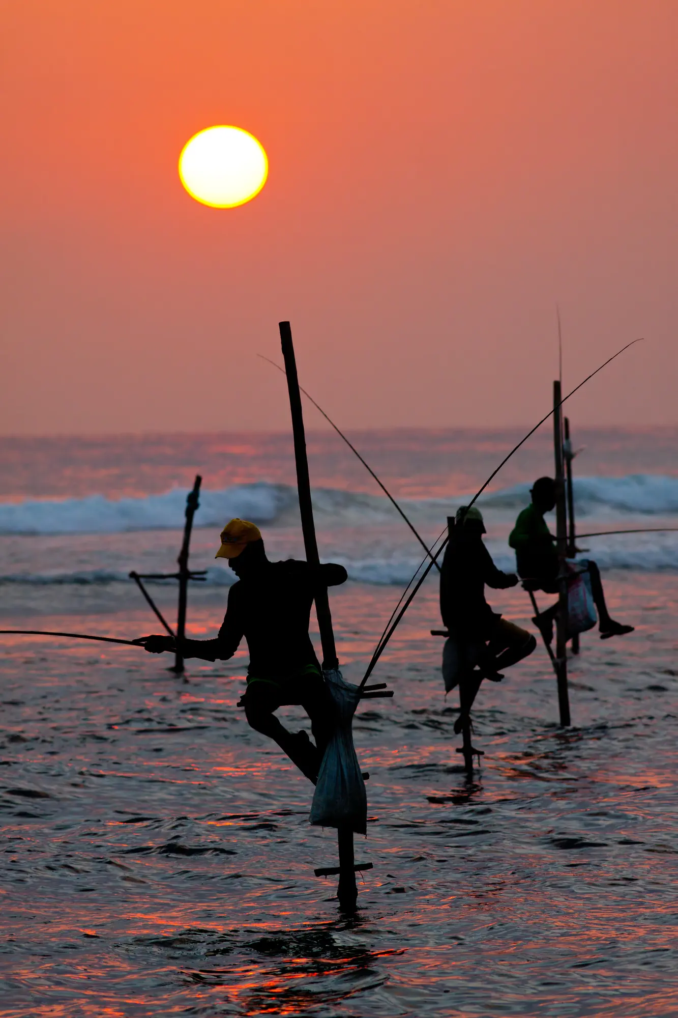 Three stilt fishermen during an orange sunset in Unawatuna, 2 weeks in Sri Lanka