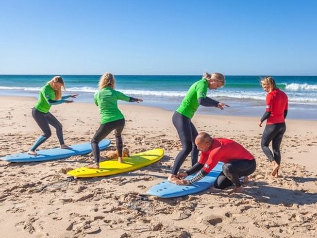 Beginner surfers wearing red and green rash guards practicing on Midigama Beach during a surf retreat in Sri Lanka. 