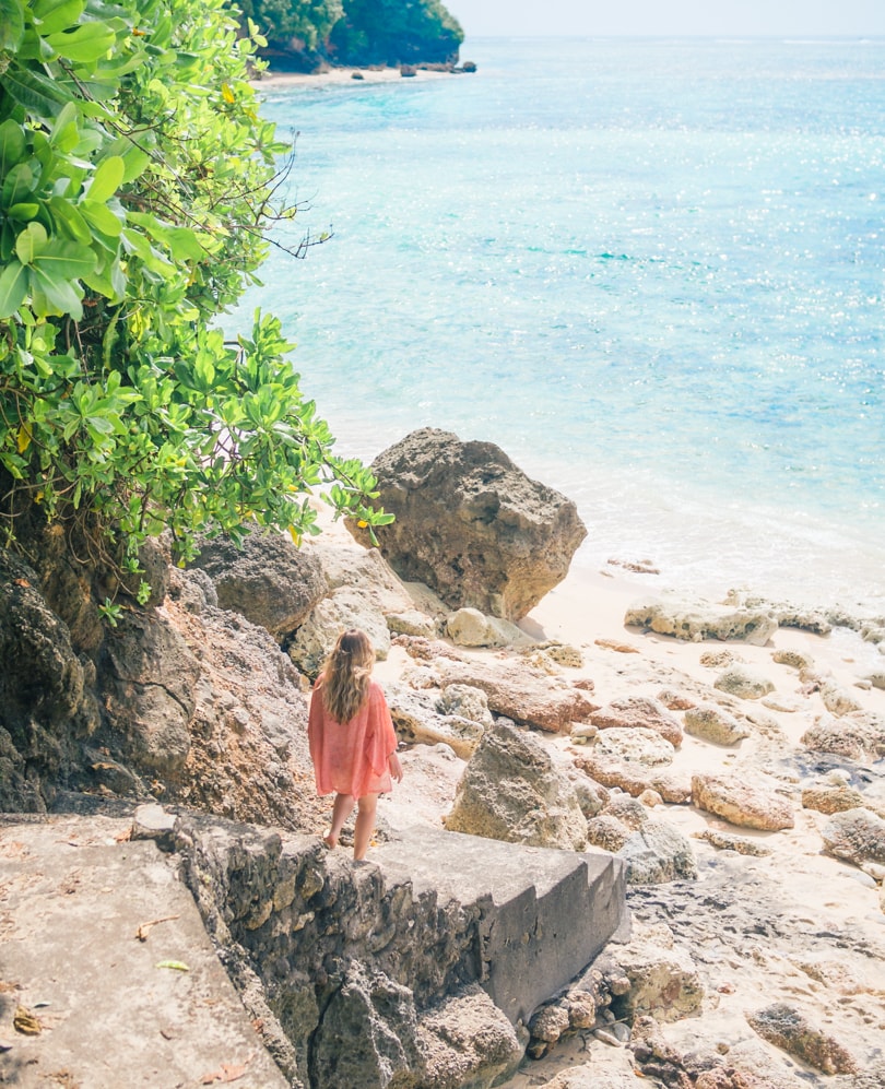 Girl in a red kimono walking down the stairs to Green Bowl Beach, one of the best beaches in Uluwatu Bali.