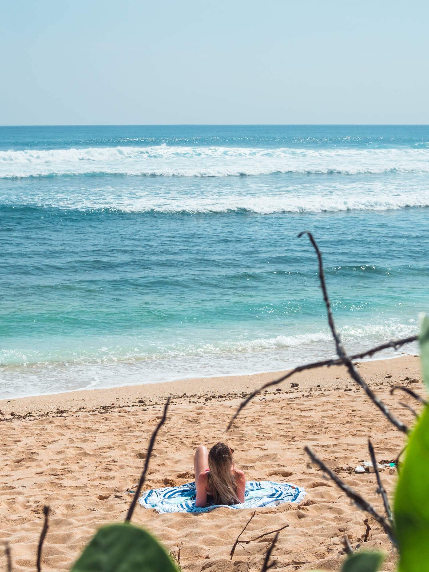 Girl lounging in the sun at Nyang Nyang Beach in Uluwatu, Bali.