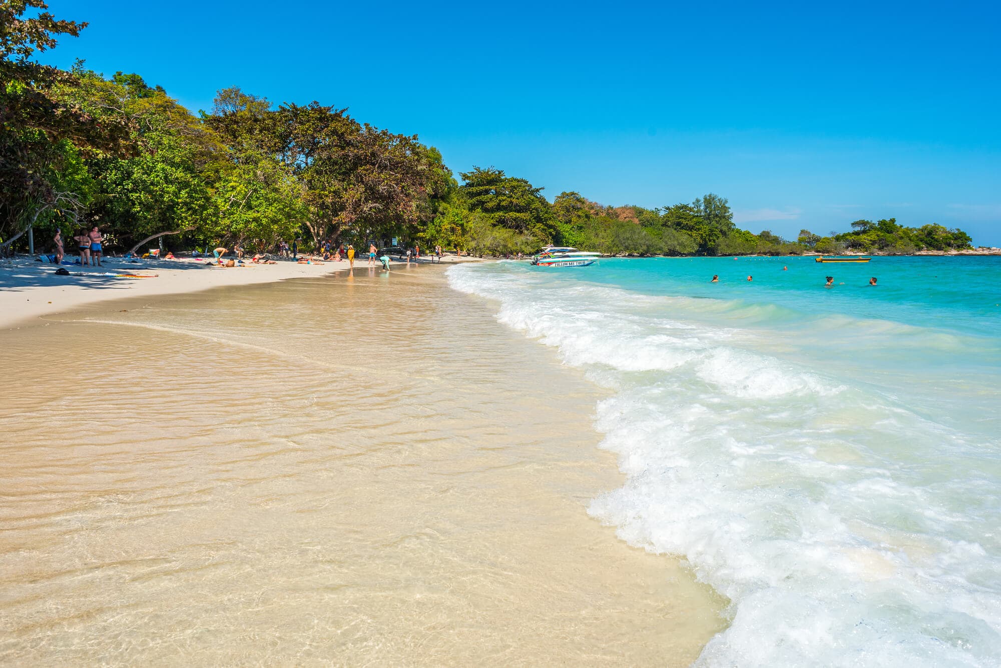 View of the beautiful white sand beach, Ao Wai, with crystal clear turquoise water and lush greenery.