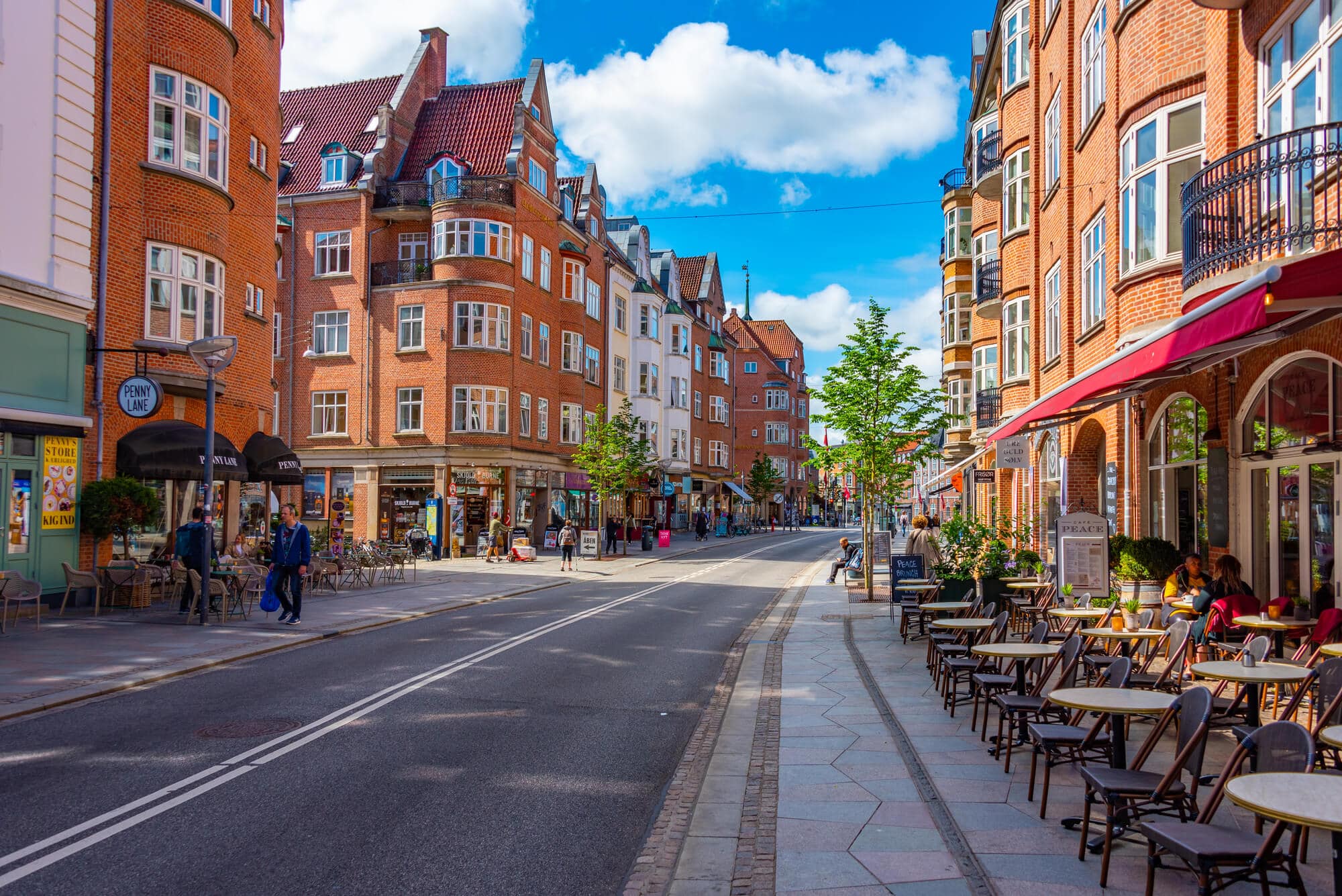 Walking down a street in Aalborg, lined by orange brick town houses and sidewalk cafes, on a day trip from Aarhus.