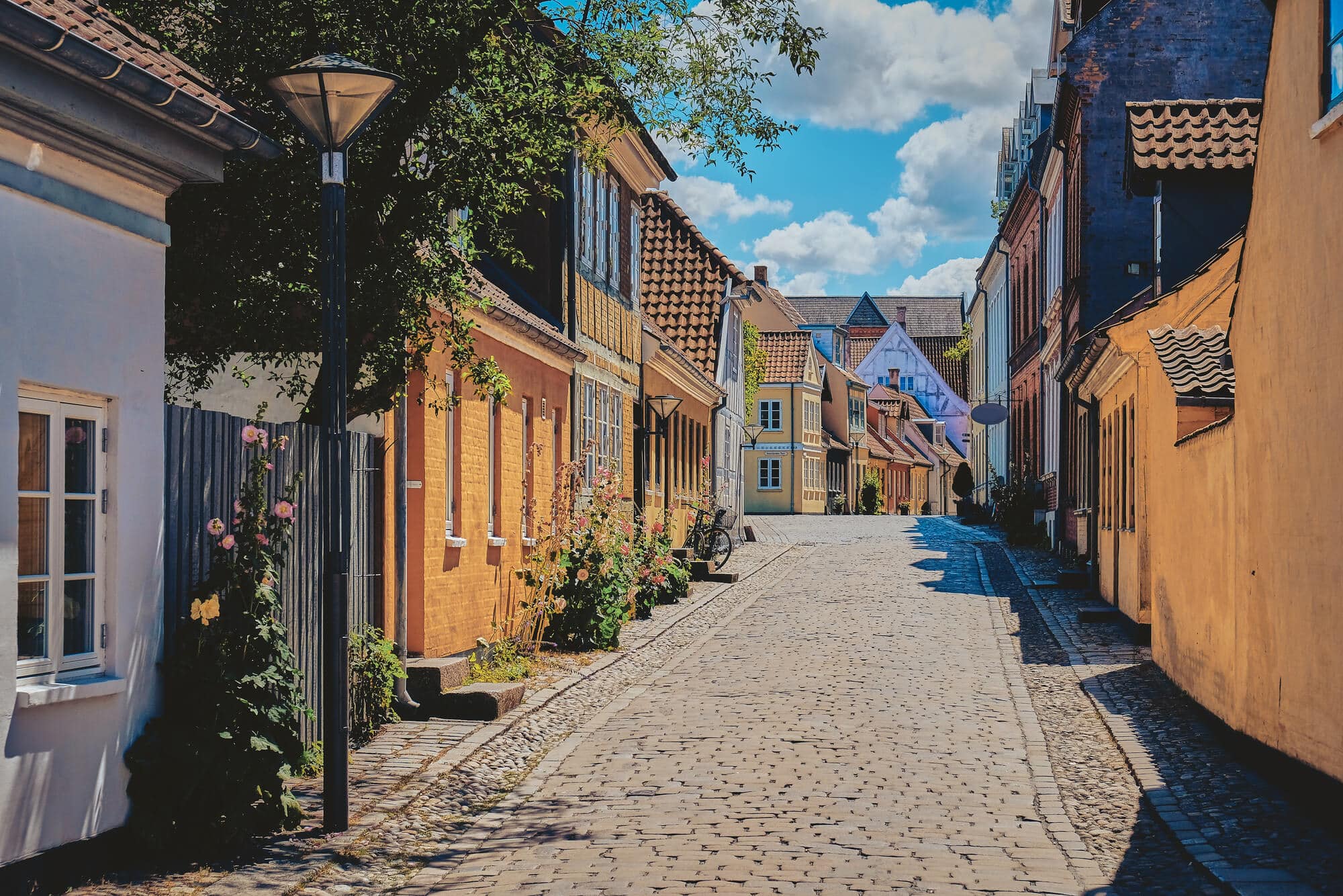 A cobbled street in Odense, lined by yellow brick houses, on a day trip from Aarhus.