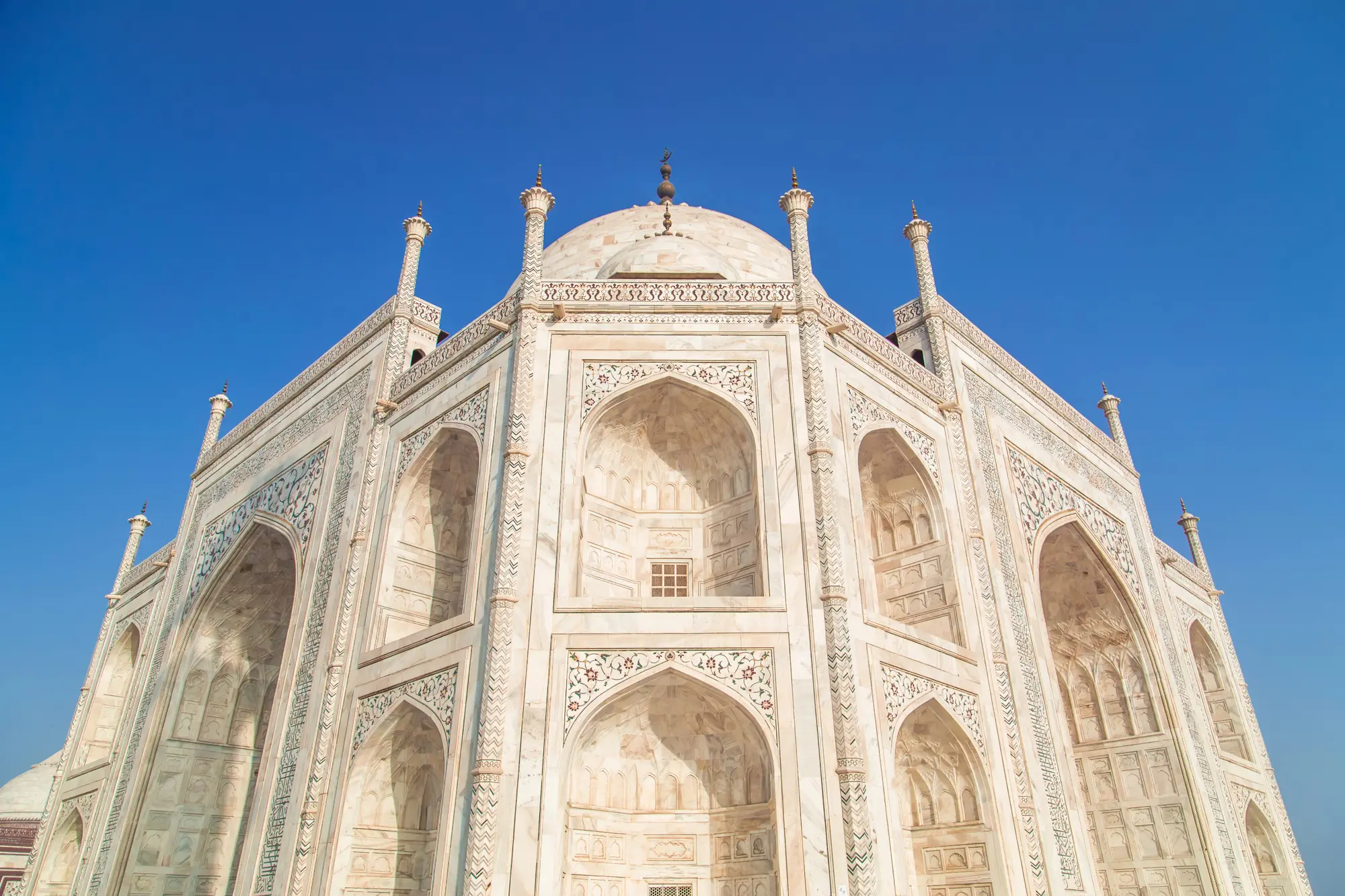 Close up of the white Taj Mahal with arches and floral design, one of my best Taj Mahal photography tips.