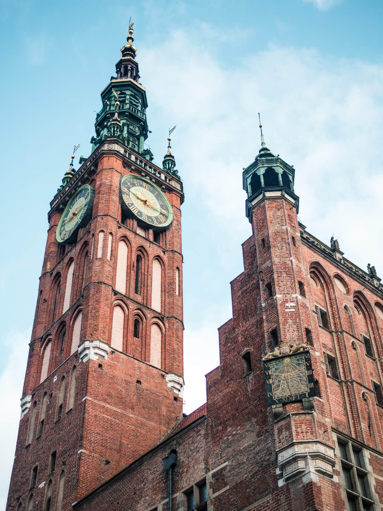 View from below of the clock tower on Gdansk Town Hall, built from red bricks, set against a blue sky, during two days in Gdansk.