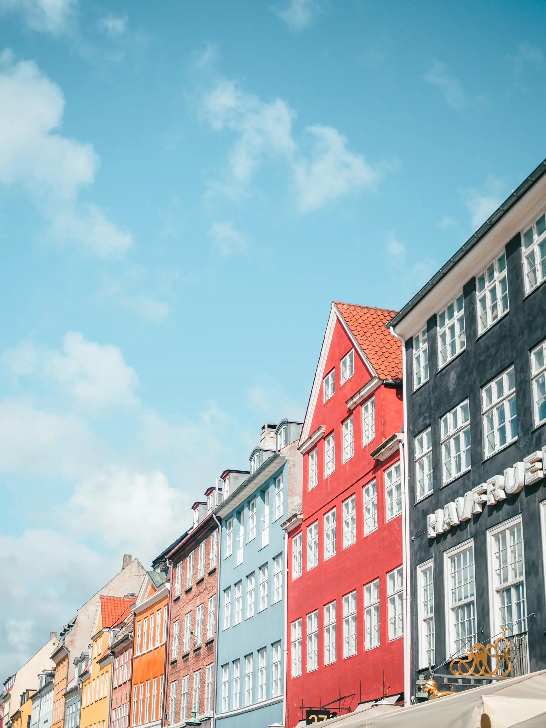 A row of colorful buildings against a blue sky in Nyhavn Copenhagen, a must on any Denmark Bucket List