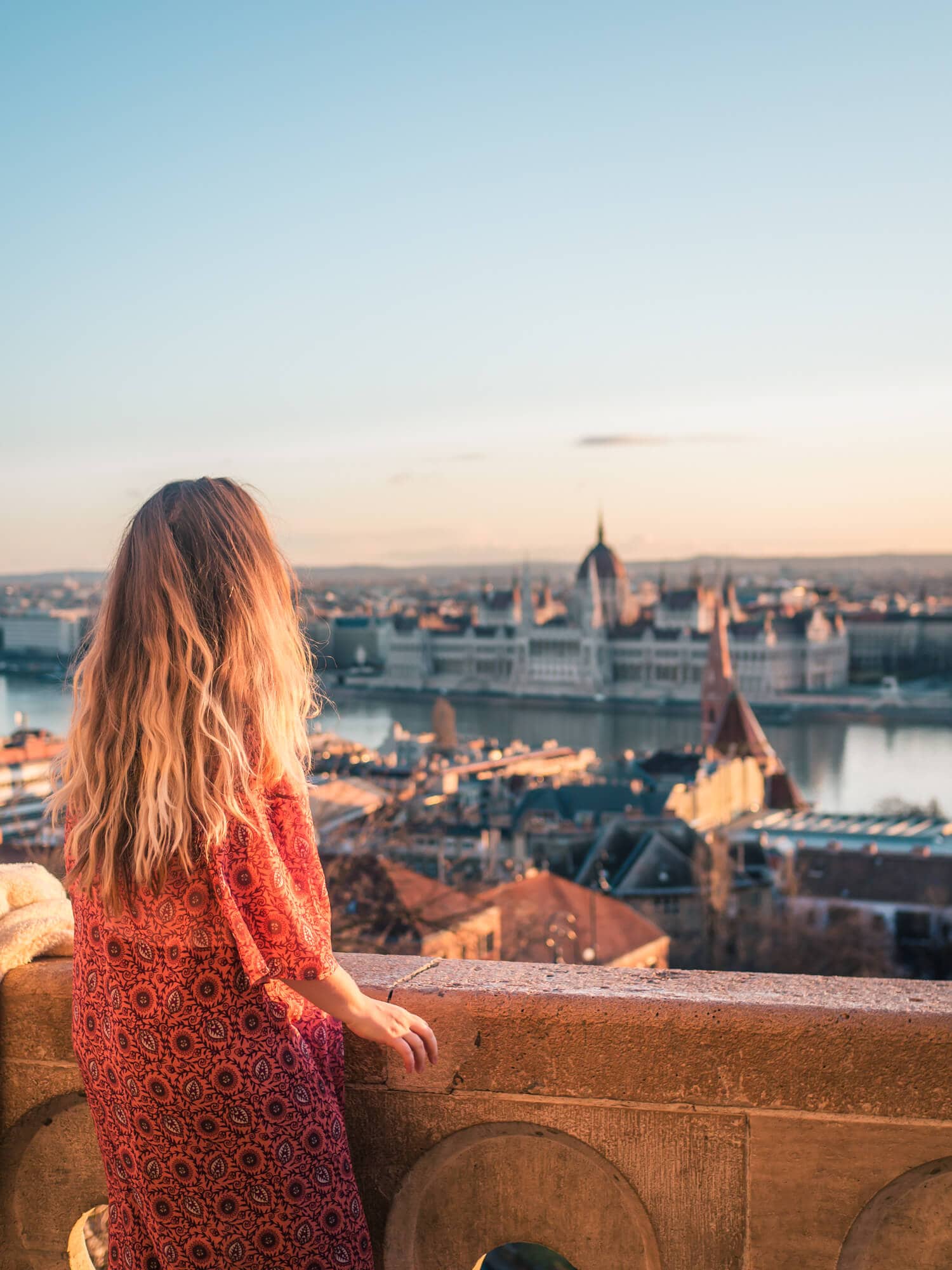 Girl with long hair wearing a pink kimono watching the sunset from Fisherman's Bastion, using the Budapest Card. Is the Budapest Card worth it?