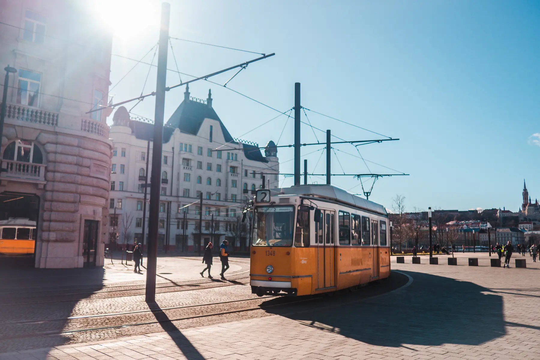 Orange and white old tram in the middle of a square in Budapest on a sunny day, best Instagram spot.