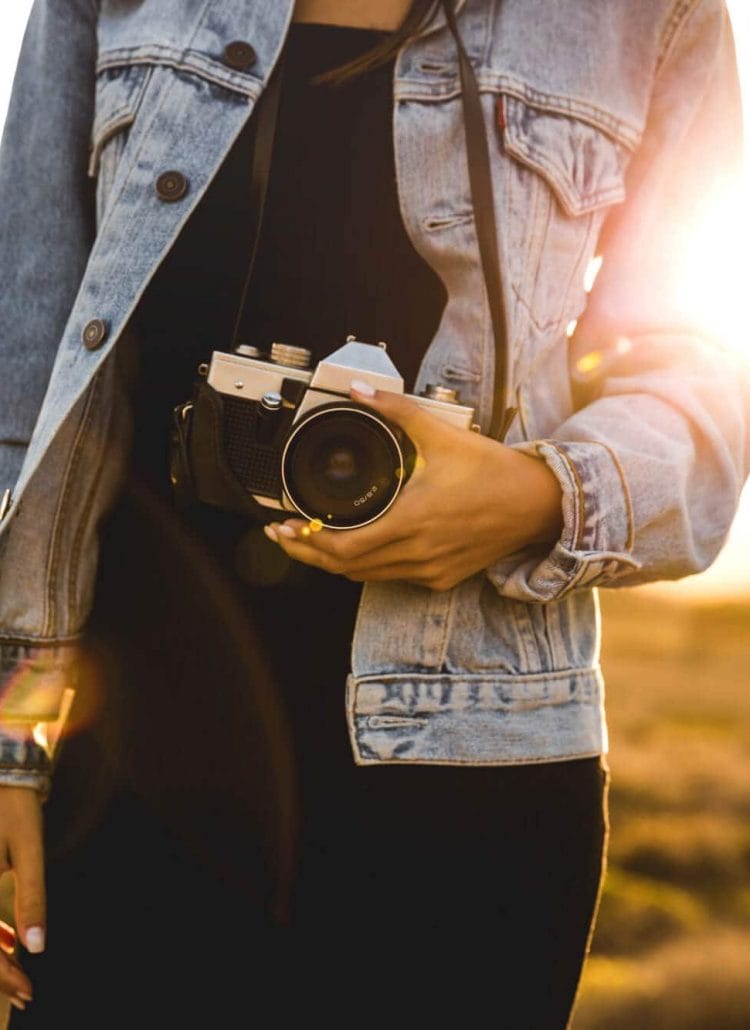 Best affordable camera for travel bloggers - Gurl holding camera at sunset
