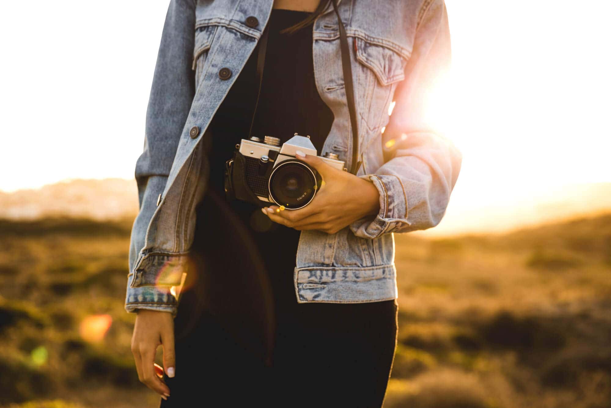Best affordable camera for travel bloggers and creators - Girl holding camera at sunset