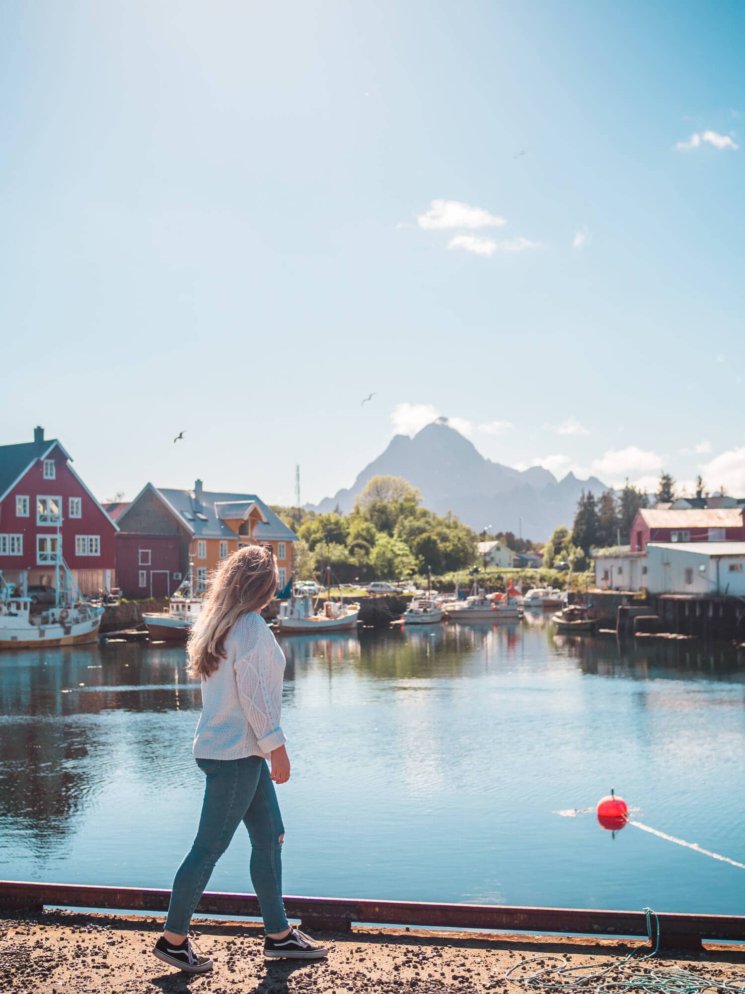 Norway Budget Breakdown - Girl walking along a harbor in Lofoten Norway.