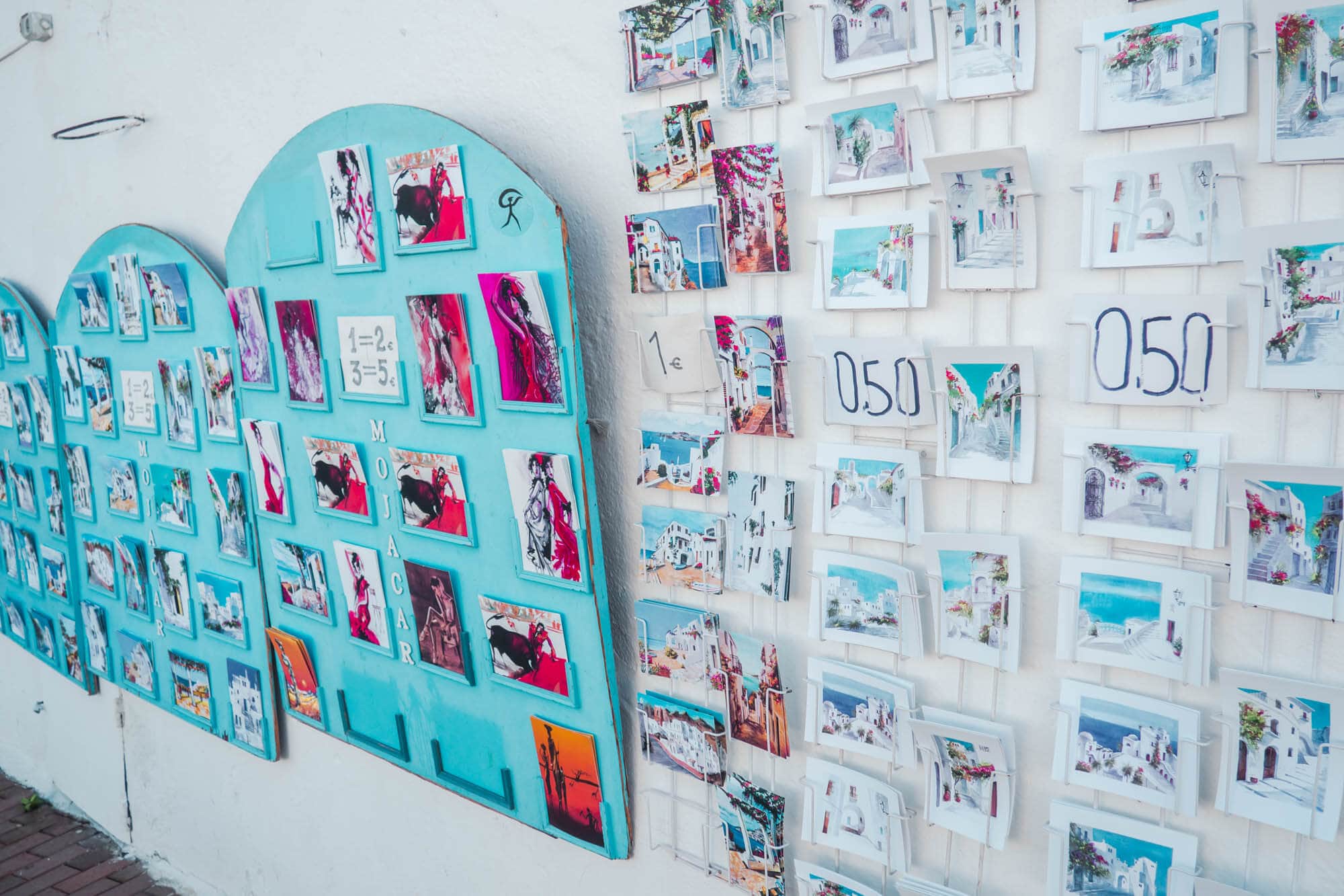 White wall displaying cards with watercolor motives from Mojacar Pueblo, Spain's most beautiful white village.