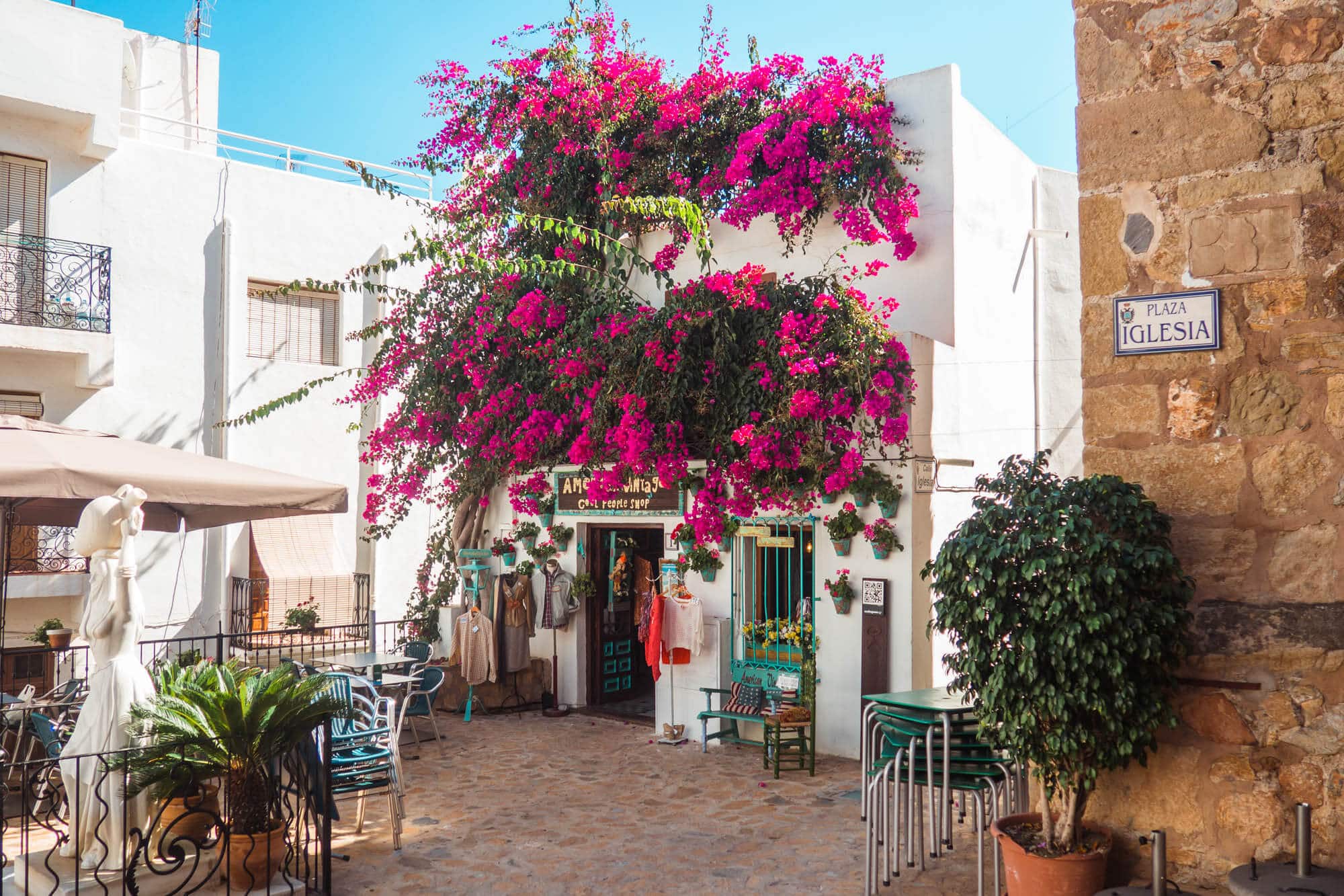 View of a beautiful white house covered in pink Bougainvillea and the Statue of Mojaquera in Plaza Iglesia in Mojacár Pueblo Spain