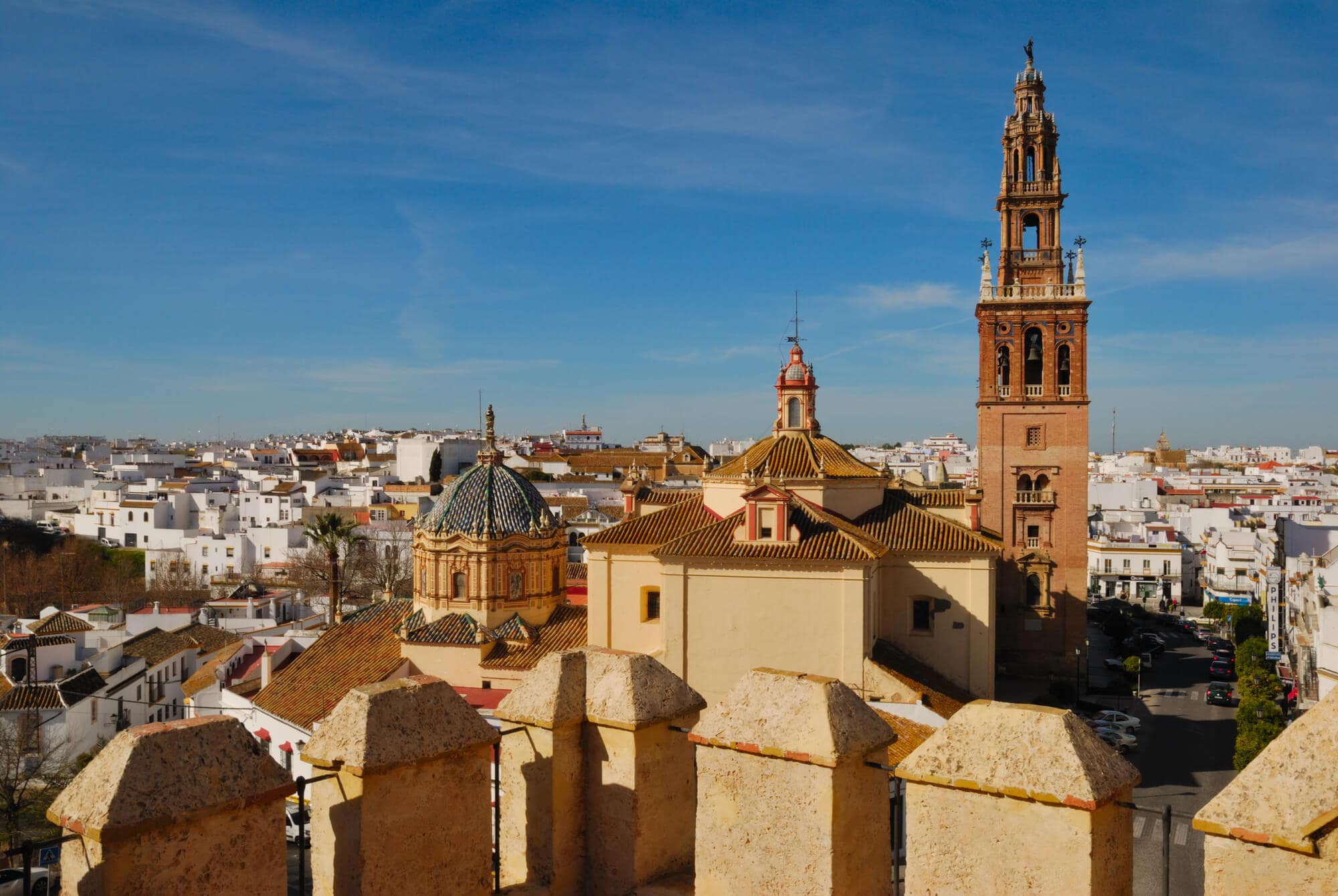 View from an old balcony over the white and golden rooftops in Carmona, Andalucía and a clear blue sky - A hidden gem and secret in Spain