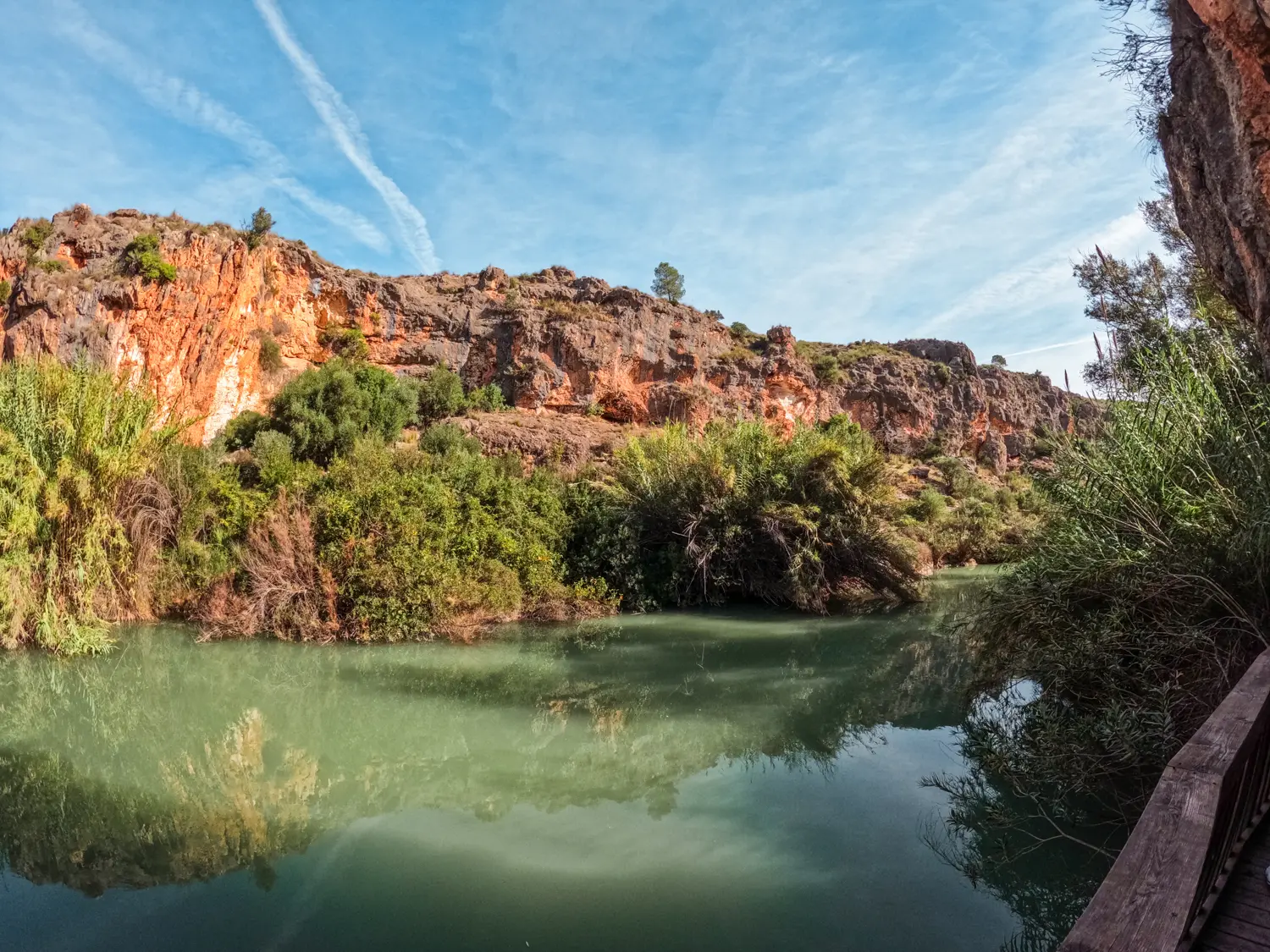 Looking out over a calm green river with mountains covered in greenery in the background, while rafting in Murcia Spain.