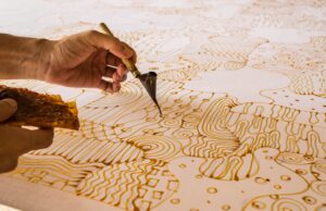 close up of two hands creating a beautiful batik patern, one of the most unusual things to do in Bali.