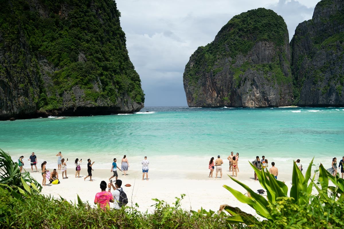 View of the white beach in Maya Bay (Phi Phi Islands) lined by greenery and towering cliffs with, during one of the best tours in Krabi. 