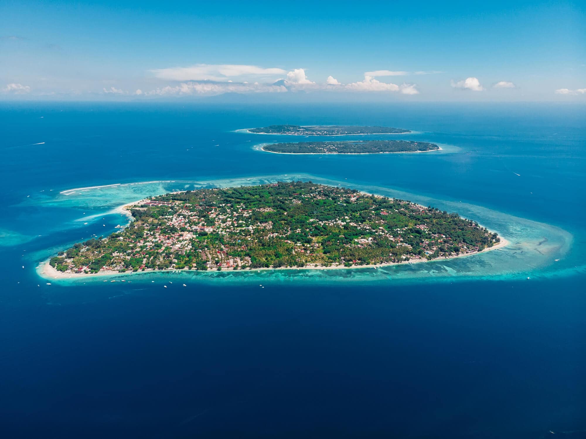 The three very green Gili Islands seen from the air, surrounded by blue water.