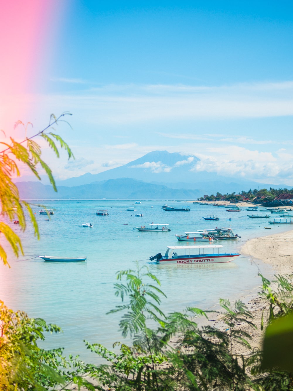 View of traditional boats at Jungut Batu Beach on Nusa Lembongan, with Bali's Mount Agung in the background.