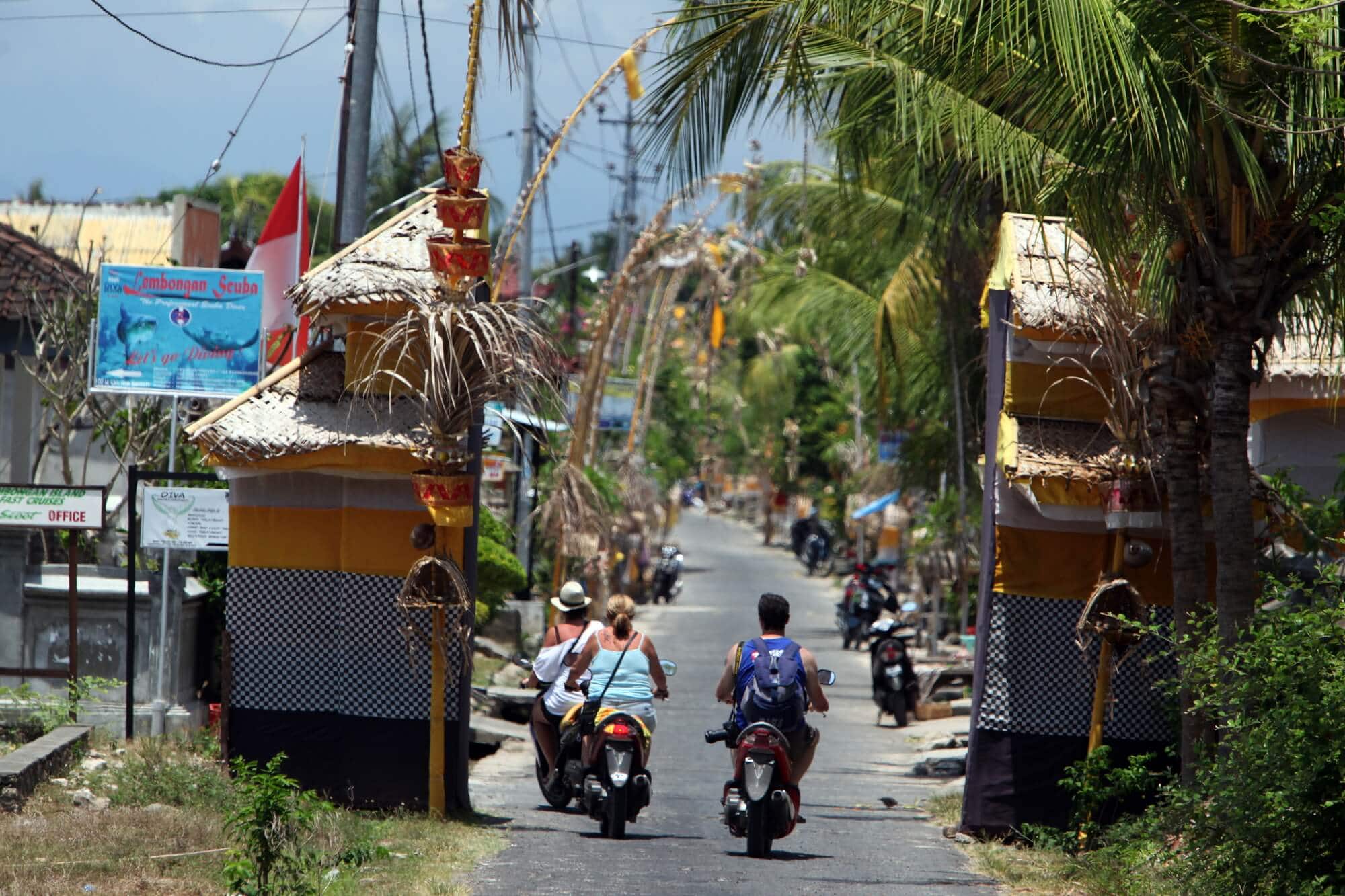 Three scooters driving down one of the main roads on Nusa Lembongan - How to get around the island