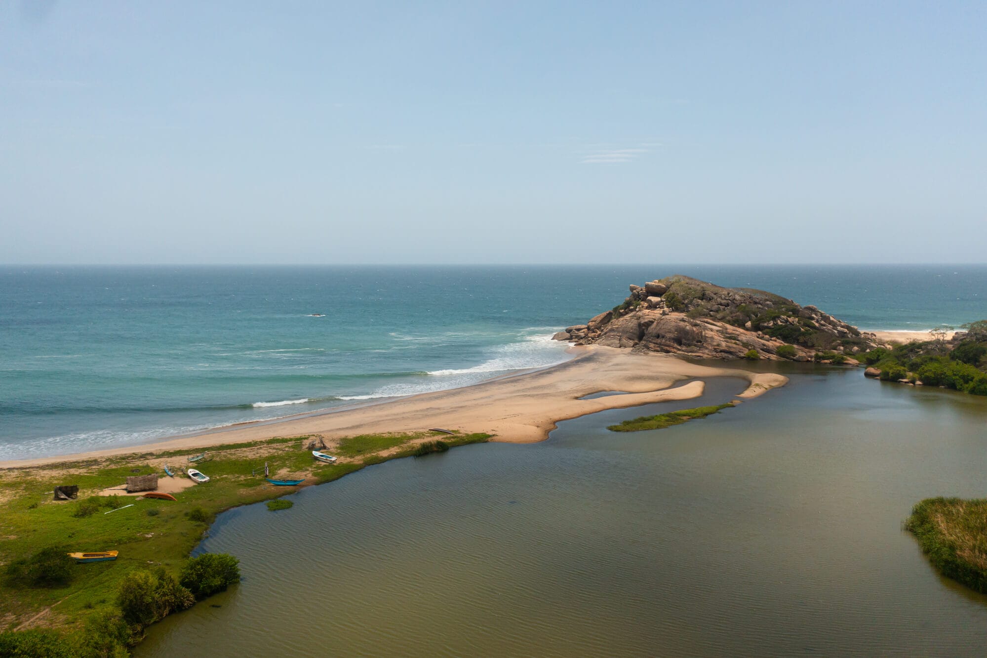 View of the ocean and a lagoon divided by a narrow sandy beach with an outcrop on one side, called Elephant Rock. One of the top things to do in Arugam Bay Sri Lanka.