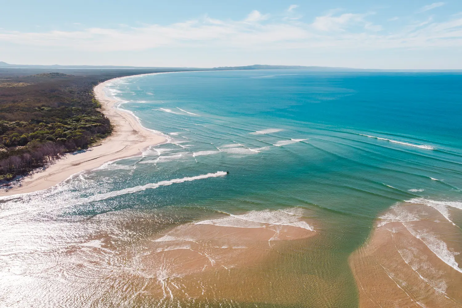 Drone view of person on a jet ski at Noosa River Mouth with blue glistening water and sand banks, one of the top things to do in Noosa.