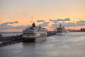 Two cruise ships docked at Barcelona cruise port at sunset.