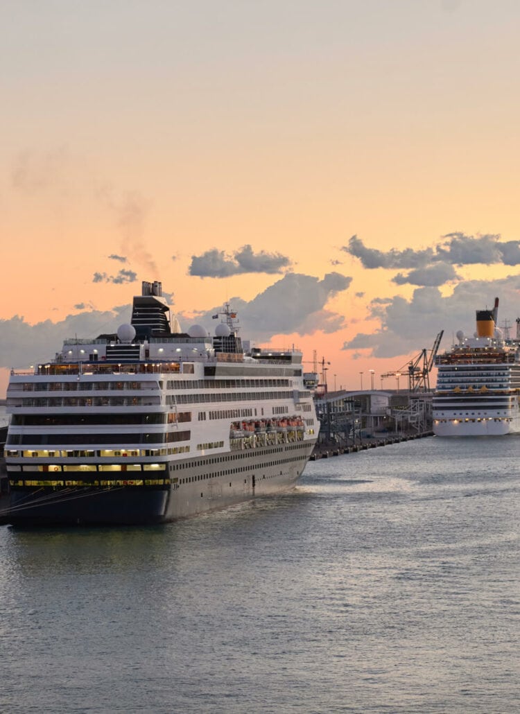 Two cruise ships docked at Barcelona cruise port at sunset.