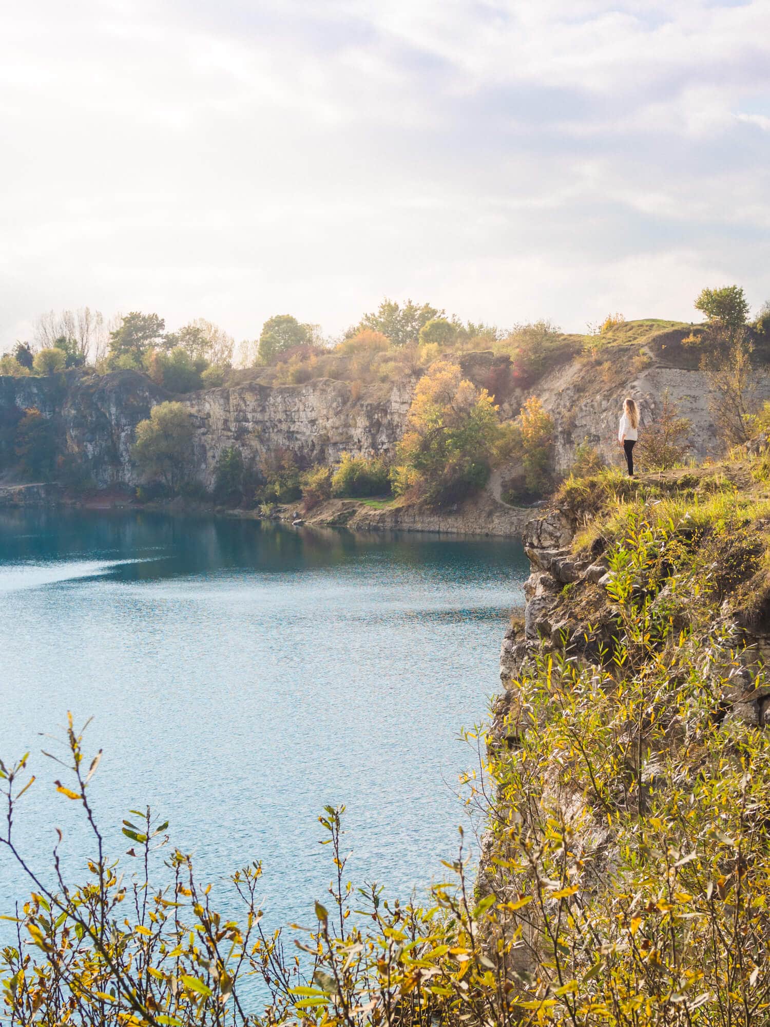 Girl standing on the edge of Zakrzówek Quarry, looking out over the Lake outside Krakow. One of the top reasons to visit Poland.