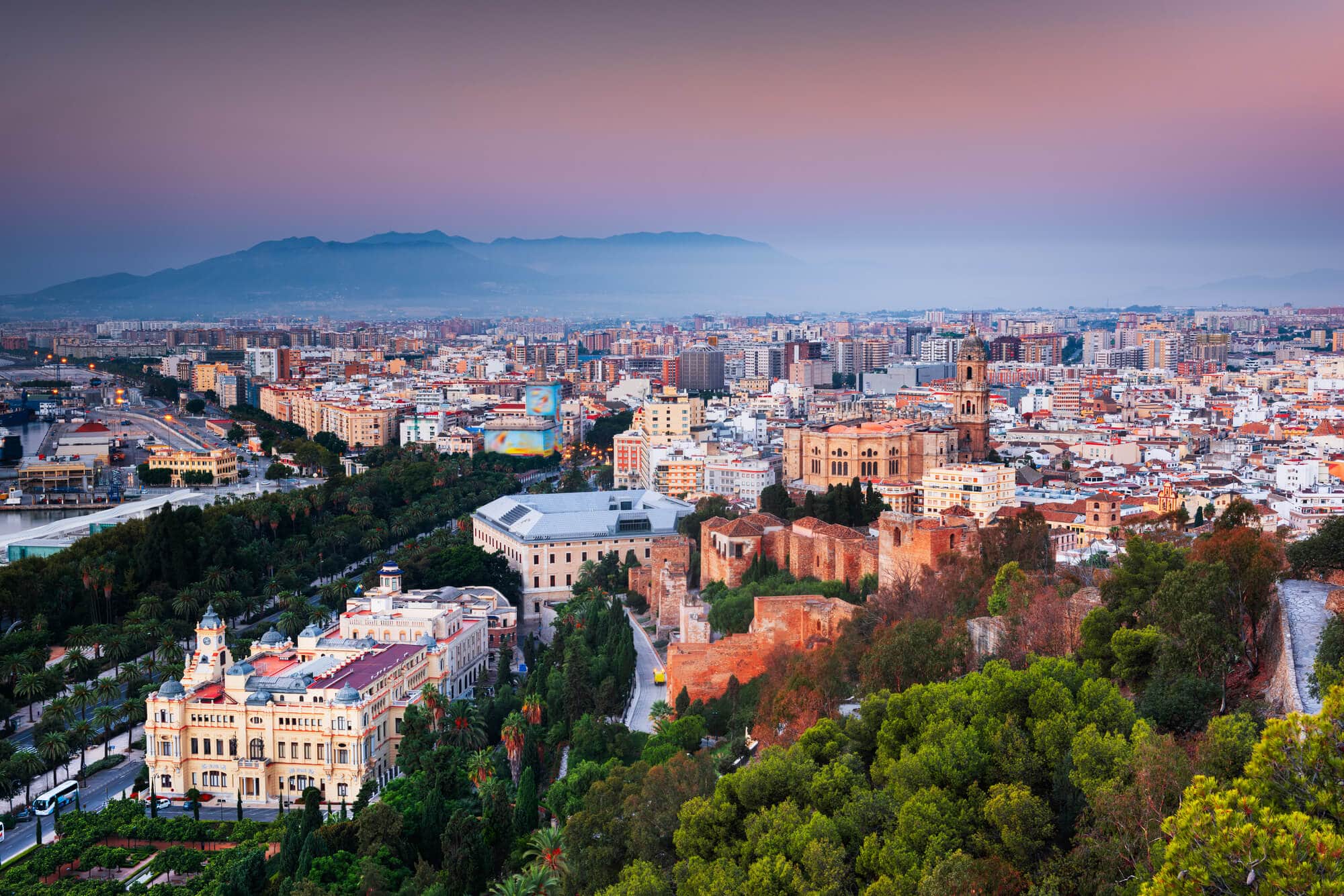 View of Malaga city during a misty pink sunset sunset seen from Mirador De Gibralfaro.