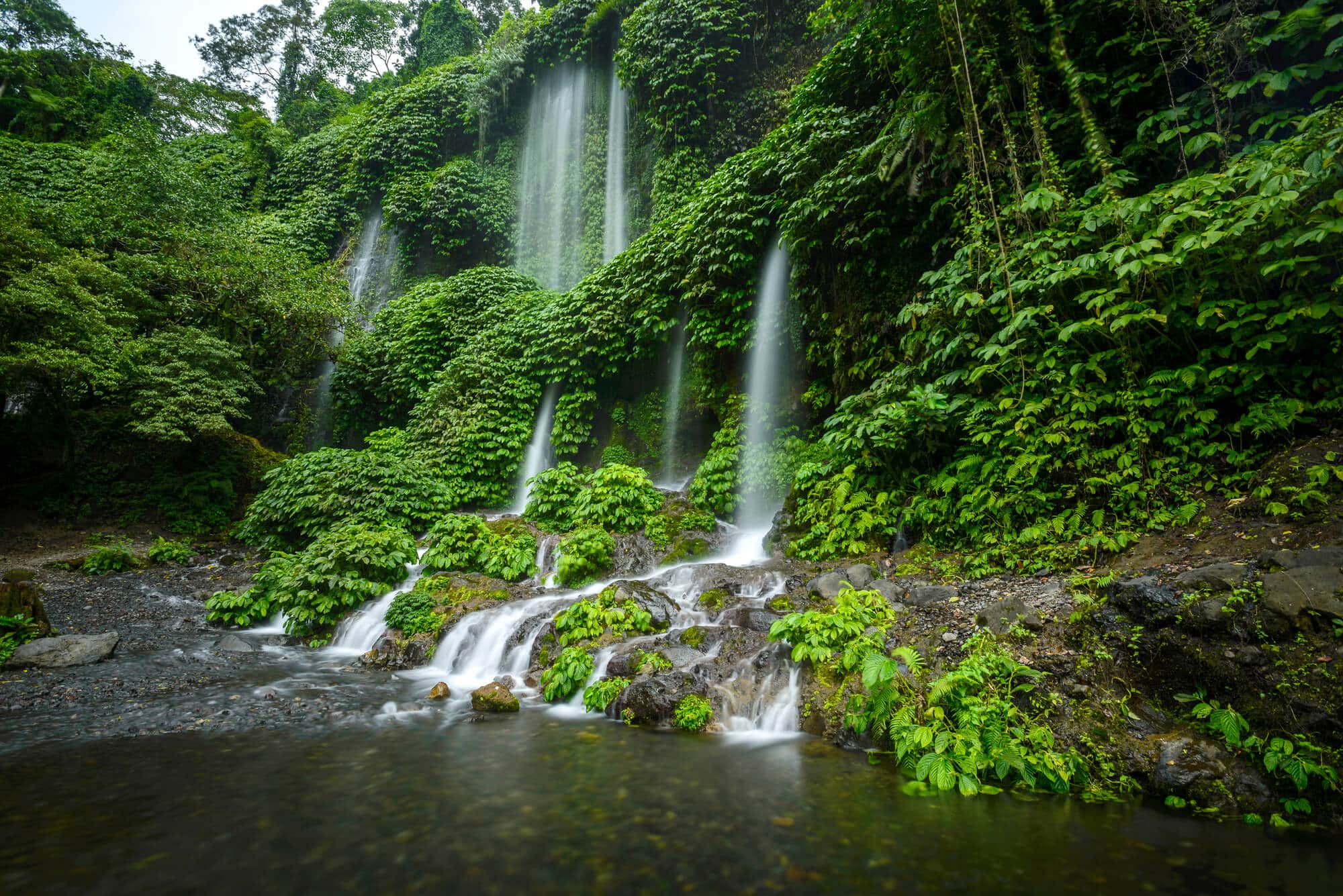 The 5 cascades of Benang Kelambu Waterfall flowing through the lush jungle into a small pool at the bottom, one of the top things to do in Lombok.