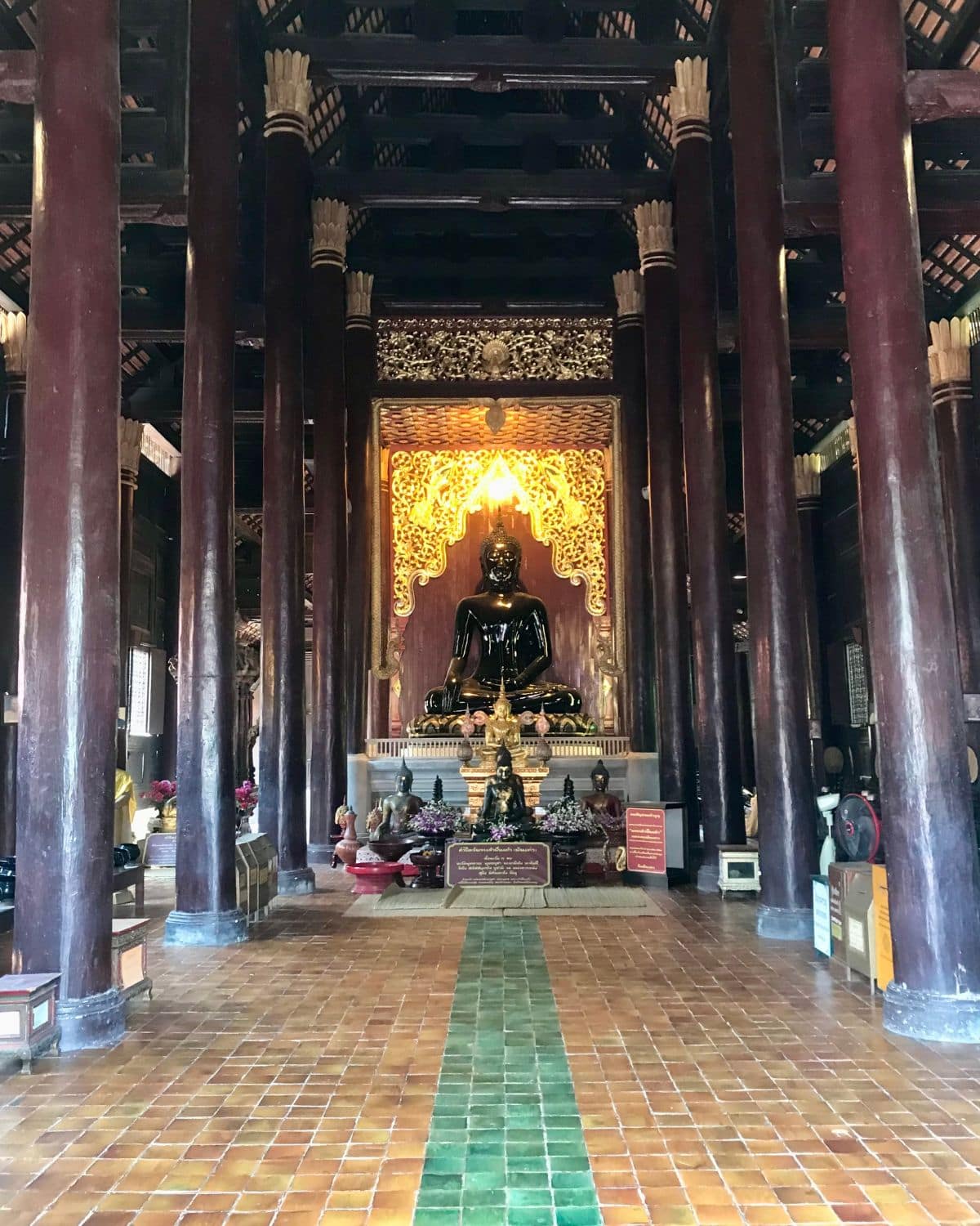 Brown columns leading to a Buddha shrine inside Wat Phan Tao temple in Chiang Mai, Thailand.