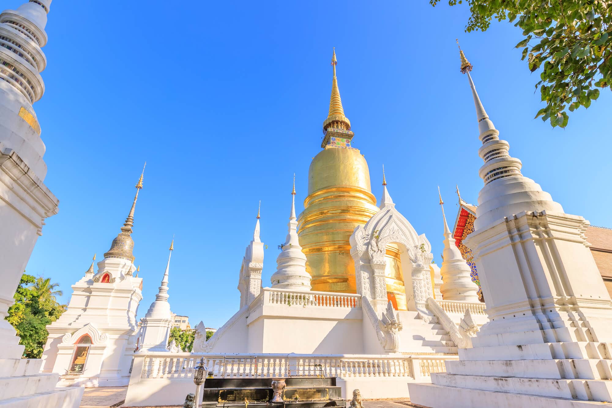 White and gold chedis against the blue sky at the impressive Wat Suan Dok temple in Chiang Mai.