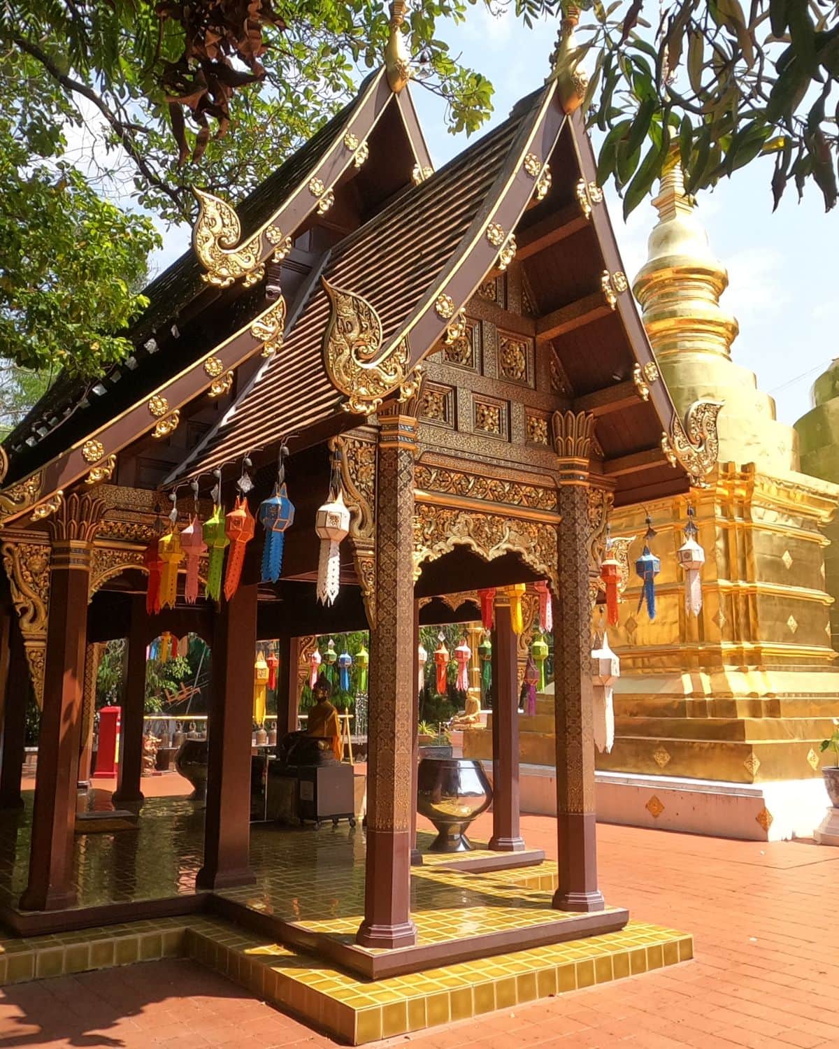 Wood shrine decorated with gold ornaments in front of a gold chedi in Wat Phra Singh, the most beautiful temples in Chiang Mai.