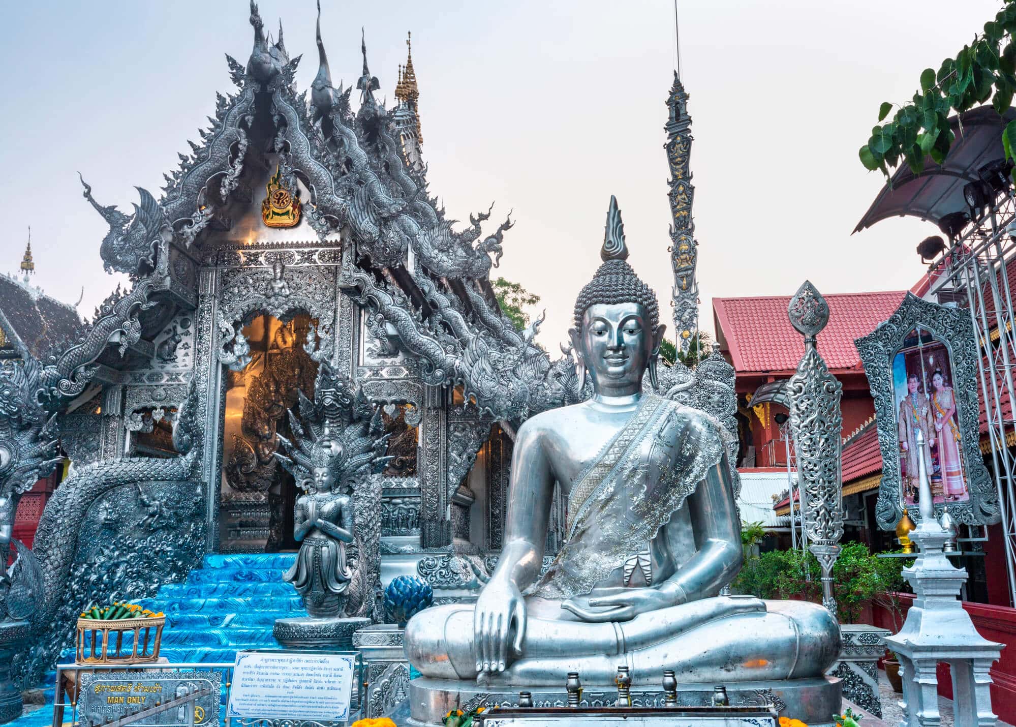 Large silver Buddha statue in front of ornate silver temple Wat Sri Suphan in Chiang Mai.