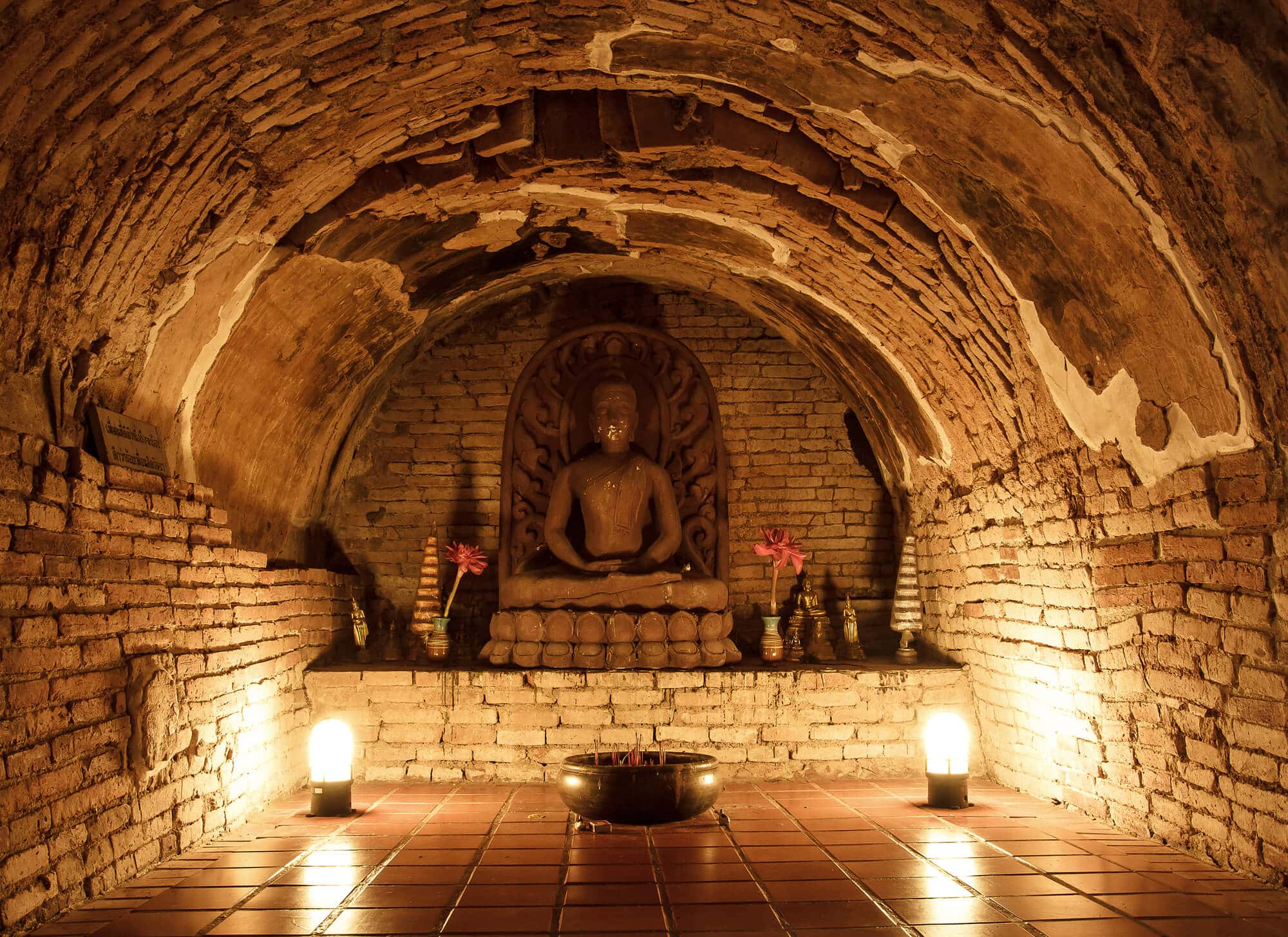 Lit up Buddha statue in underground temple Wat Umong, one of the most unique temples in Chiang Mai, Thailand.