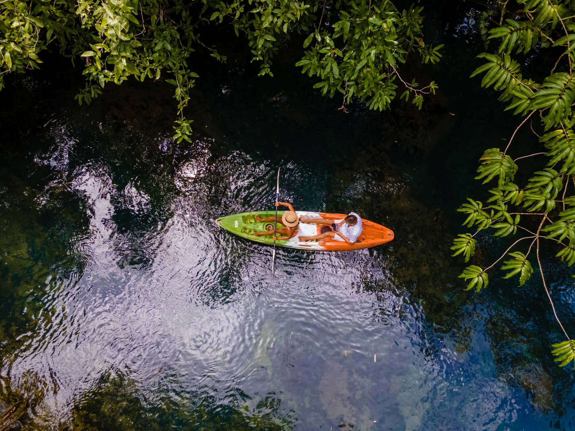Drone shot of couple on a green, white and orange kayak in the jungle of Krabi during a guided tour.