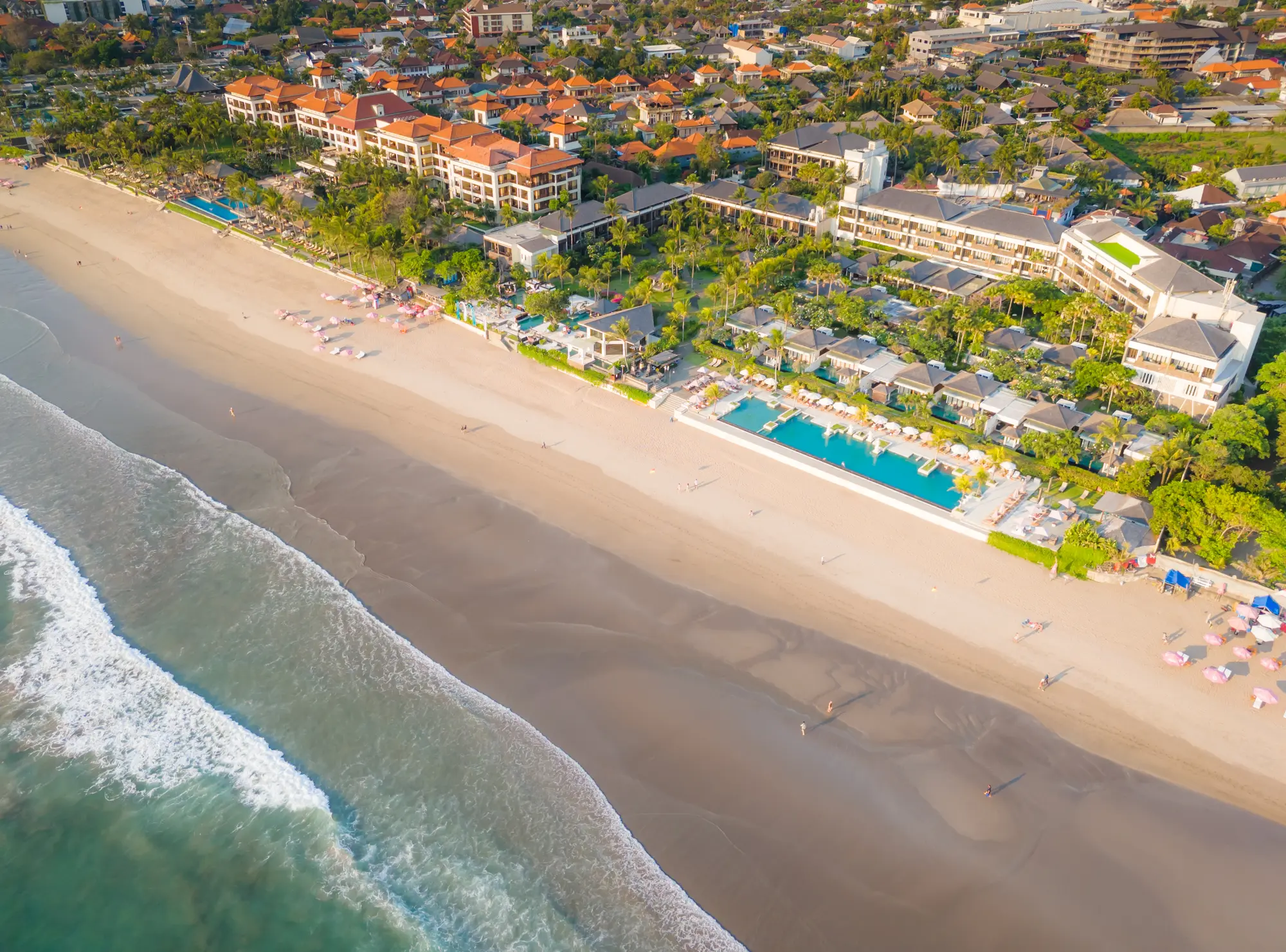 Aerial view of two large resorts with pools right on Seminyak Beach, one of the best places to stay in Bali.