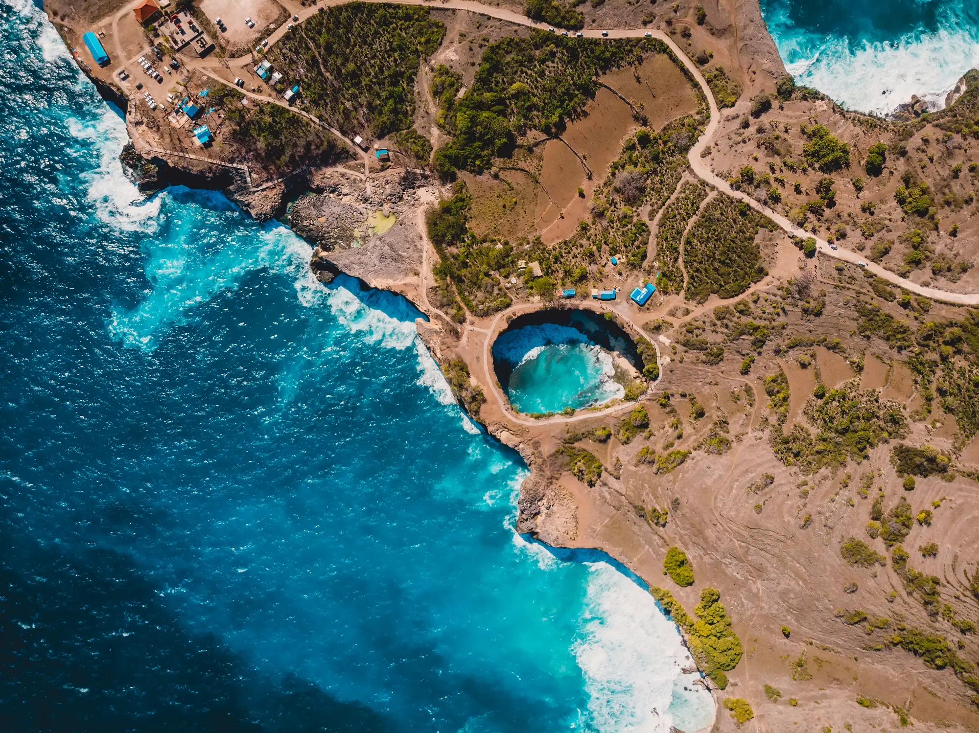 Aerial view of Broken Bay, a circular open cave next to the turquoise ocean, one of the top things to see in West Nusa Penida.