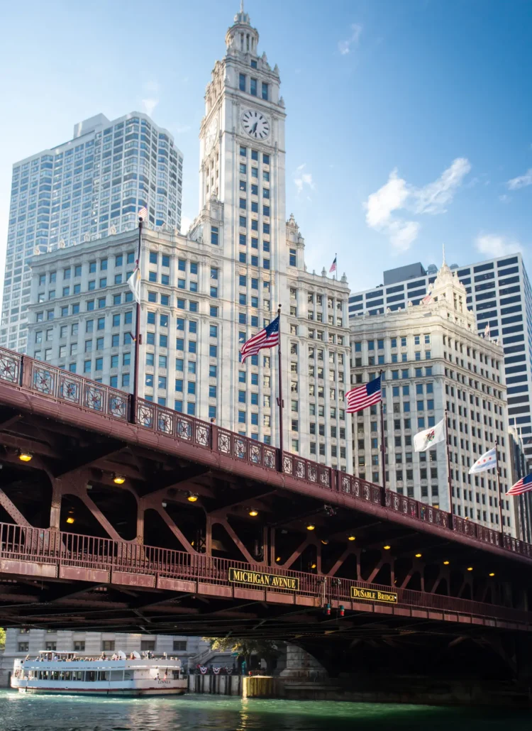 The beautiful white Wrigley building i front of the burgundy DuSable bridge with a river boat passing under, during a architectural boat tour of Chicago.