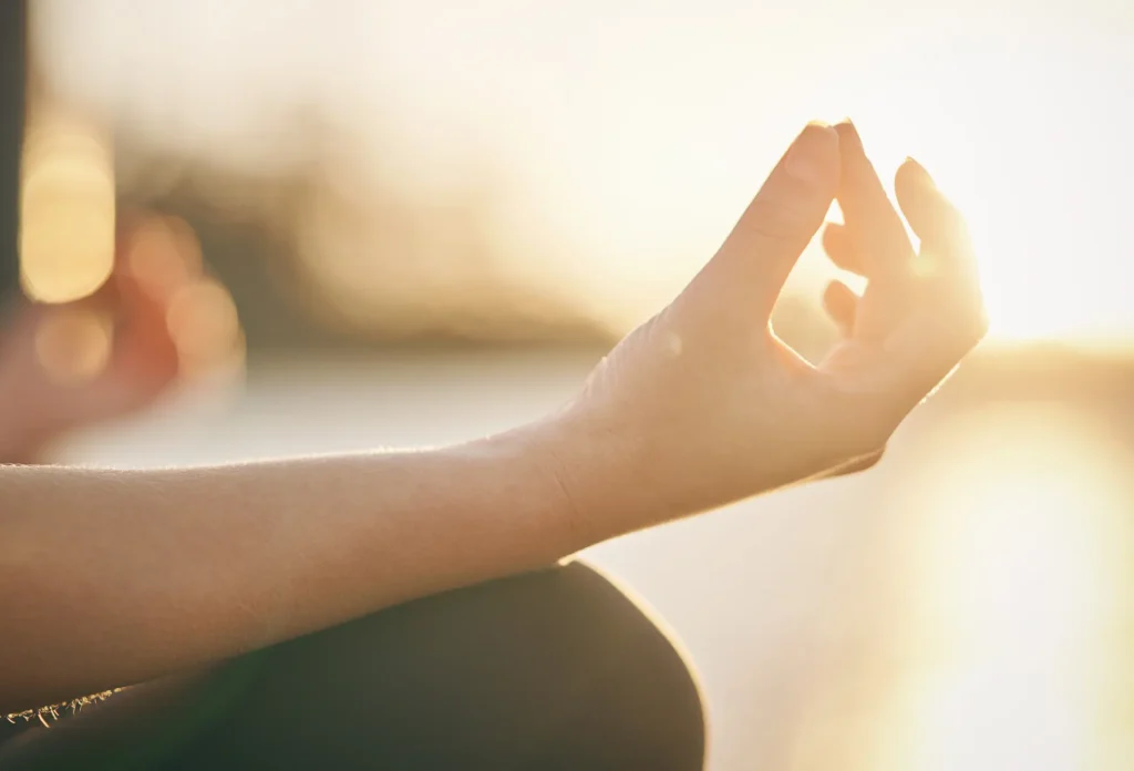 close up of woman sitting in a lotus pose during meditation at sunset. One of the best tips for overcoming fear of flying.